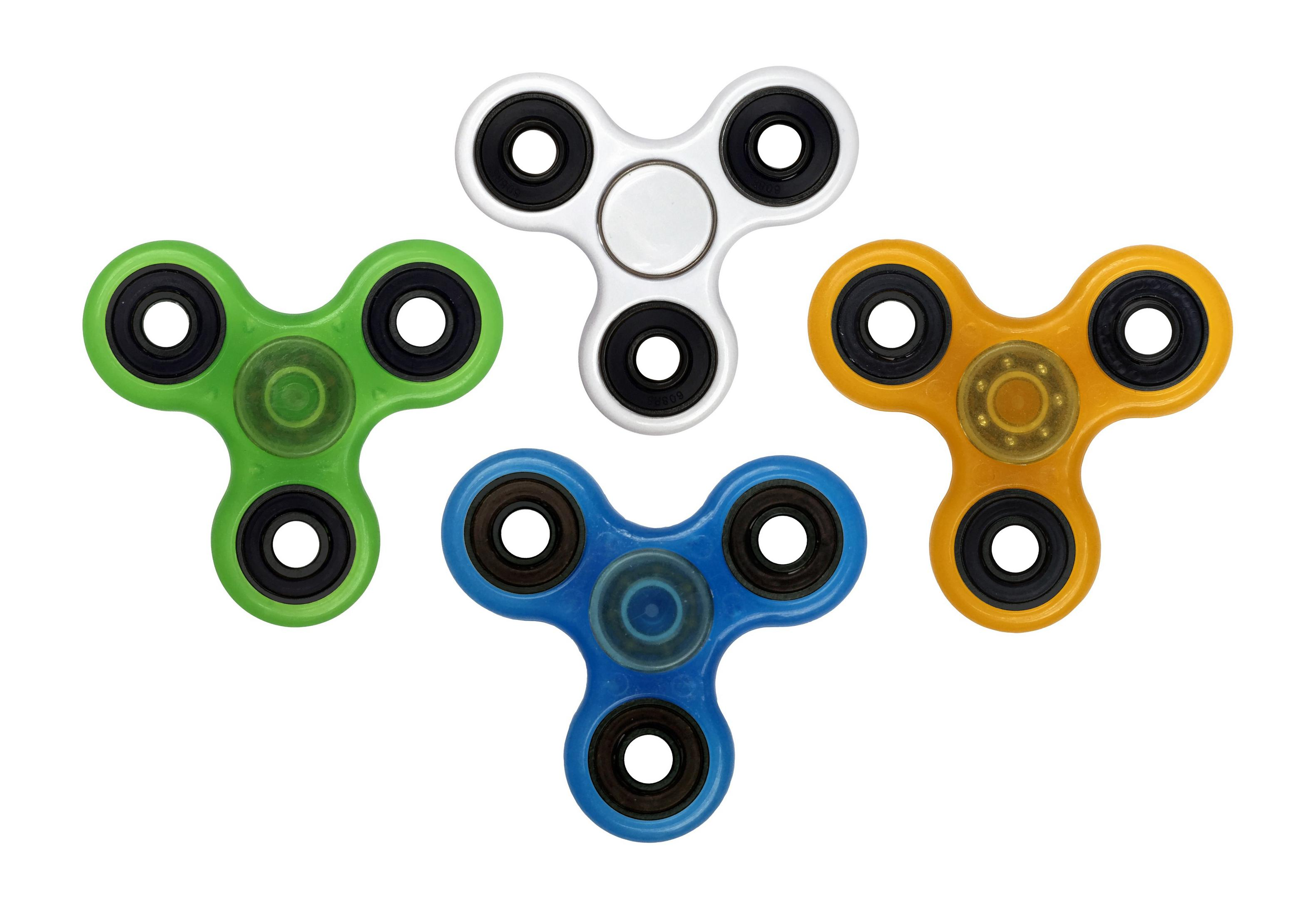 Vier Handspinner in Grün, Silber, Gelb und Blau liegen auf einem weißen Hintergrund.