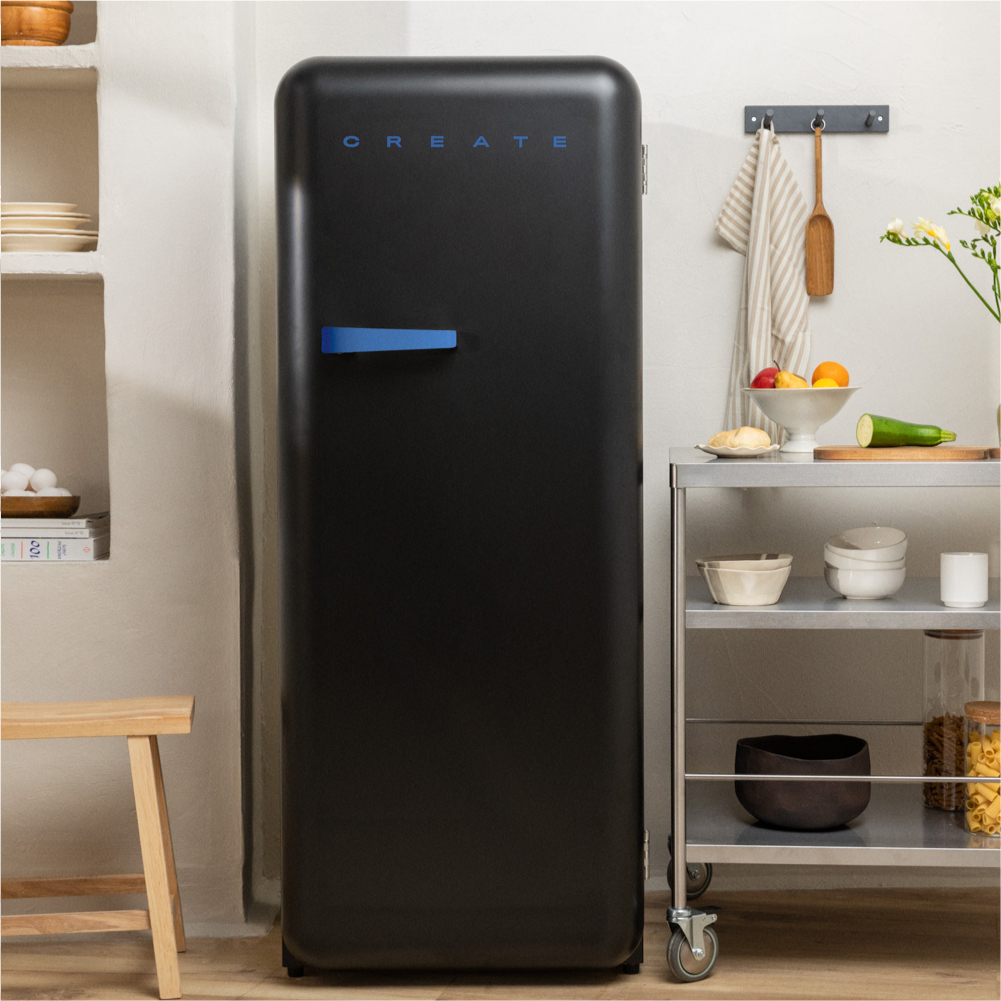 Frigorífico retro negro con asa azul, CREATE arriba. Ambiente de cocina con objetos.