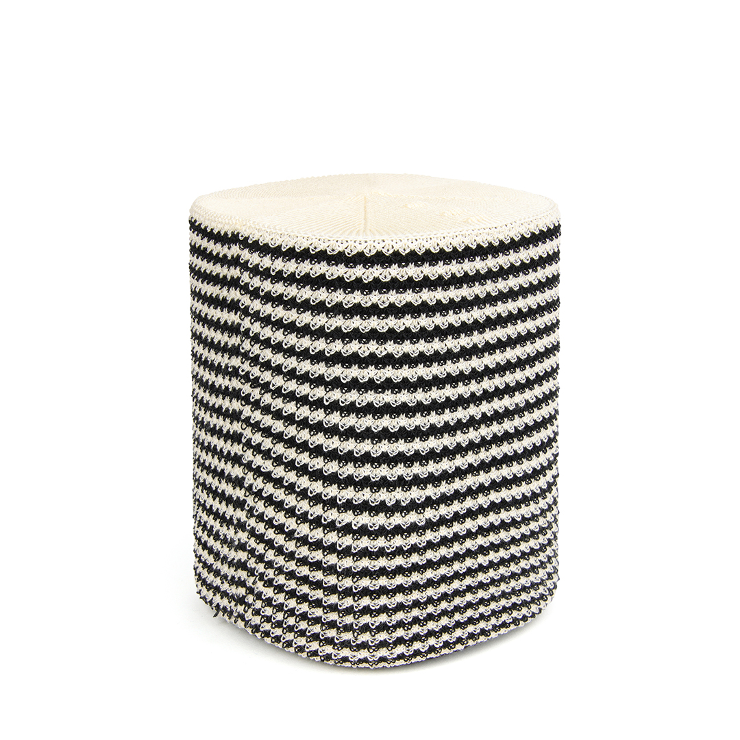 Tabouret tricoté à rayures noires et blanches sur une surface blanche.