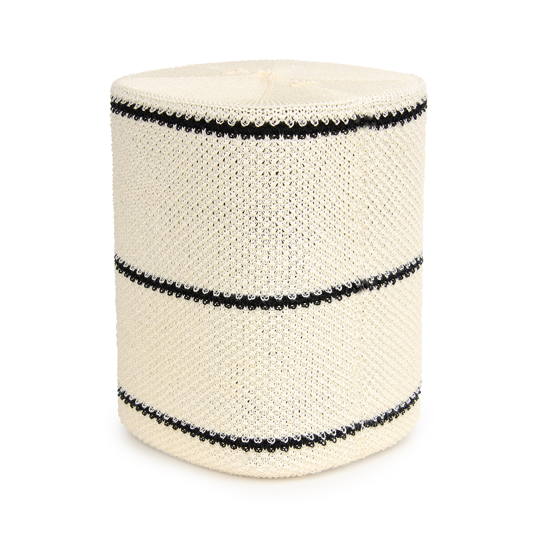 Tabouret tricoté à rayures blanches et noires sur une surface blanche.