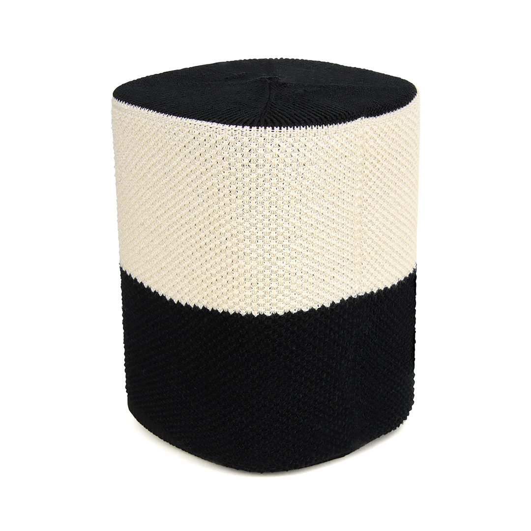 Un haut-parleur noir et blanc avec un couvercle tissé se dresse sur un fond blanc.
