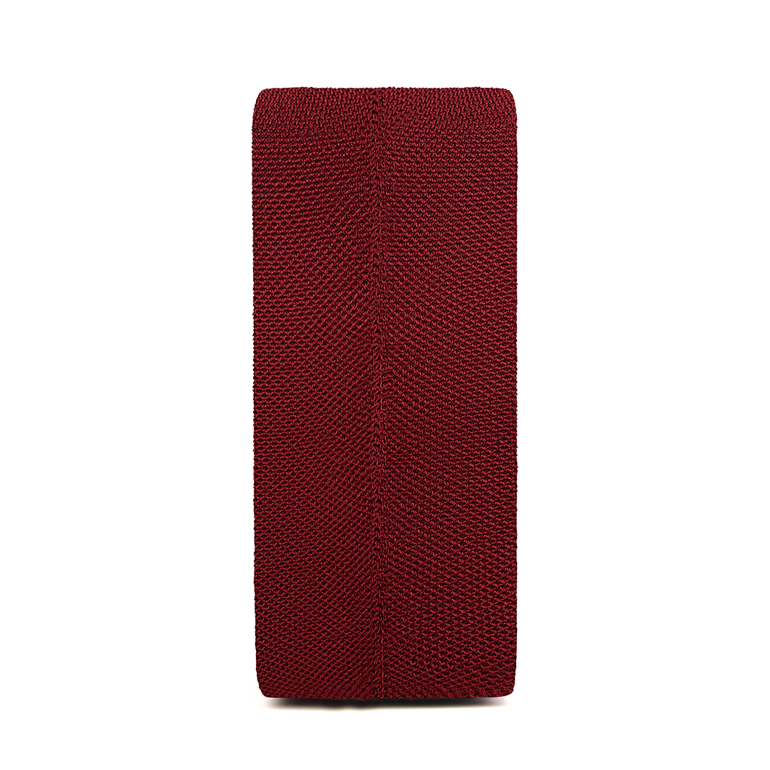 Tabouret rectangulaire tricoté marron sur une surface blanche.
