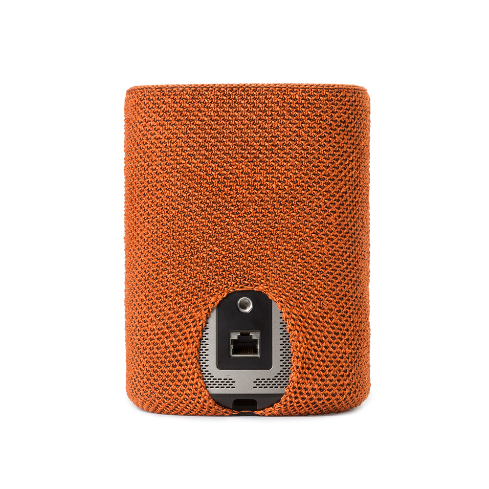 Un haut-parleur orange avec un couvercle tissé montre son panneau arrière et ses ports sur fond blanc.