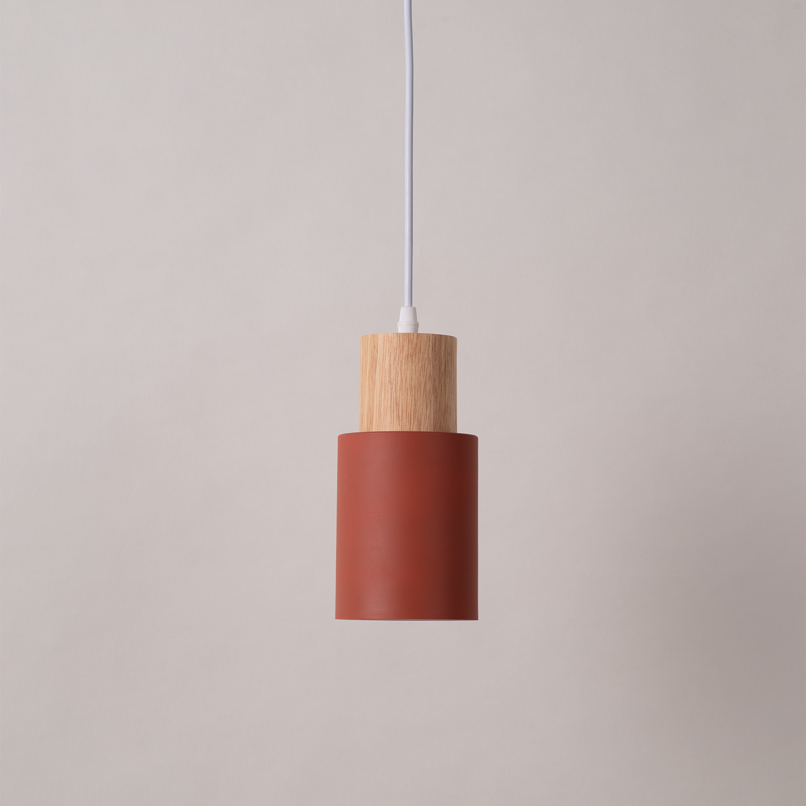 Una lámpara colgante cilíndrica cuelga, con una parte superior de madera y una sección inferior color óxido.