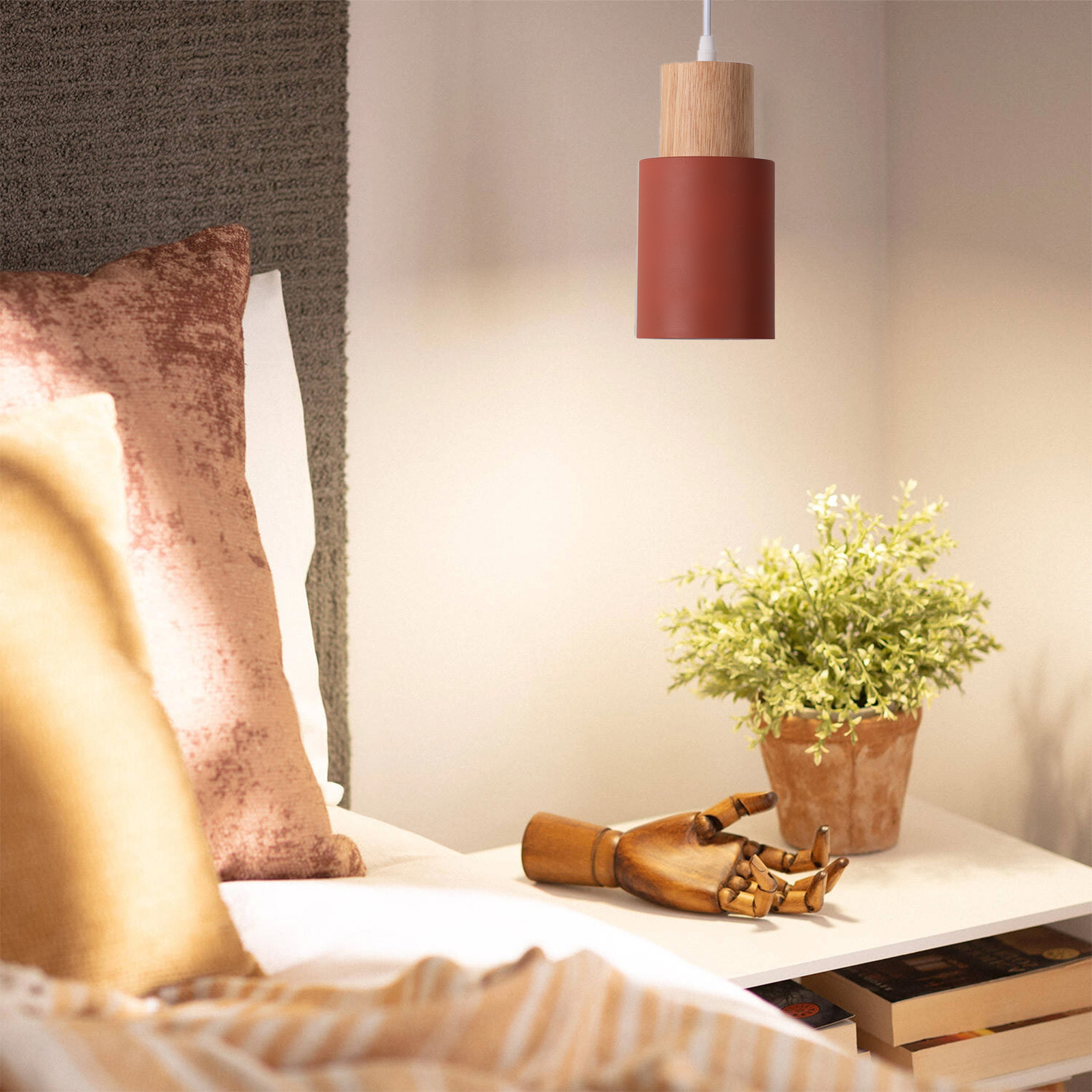 Una escena de noche muestra una lámpara colgante, una mesita de noche con libros y una planta, y una escultura de mano de madera.