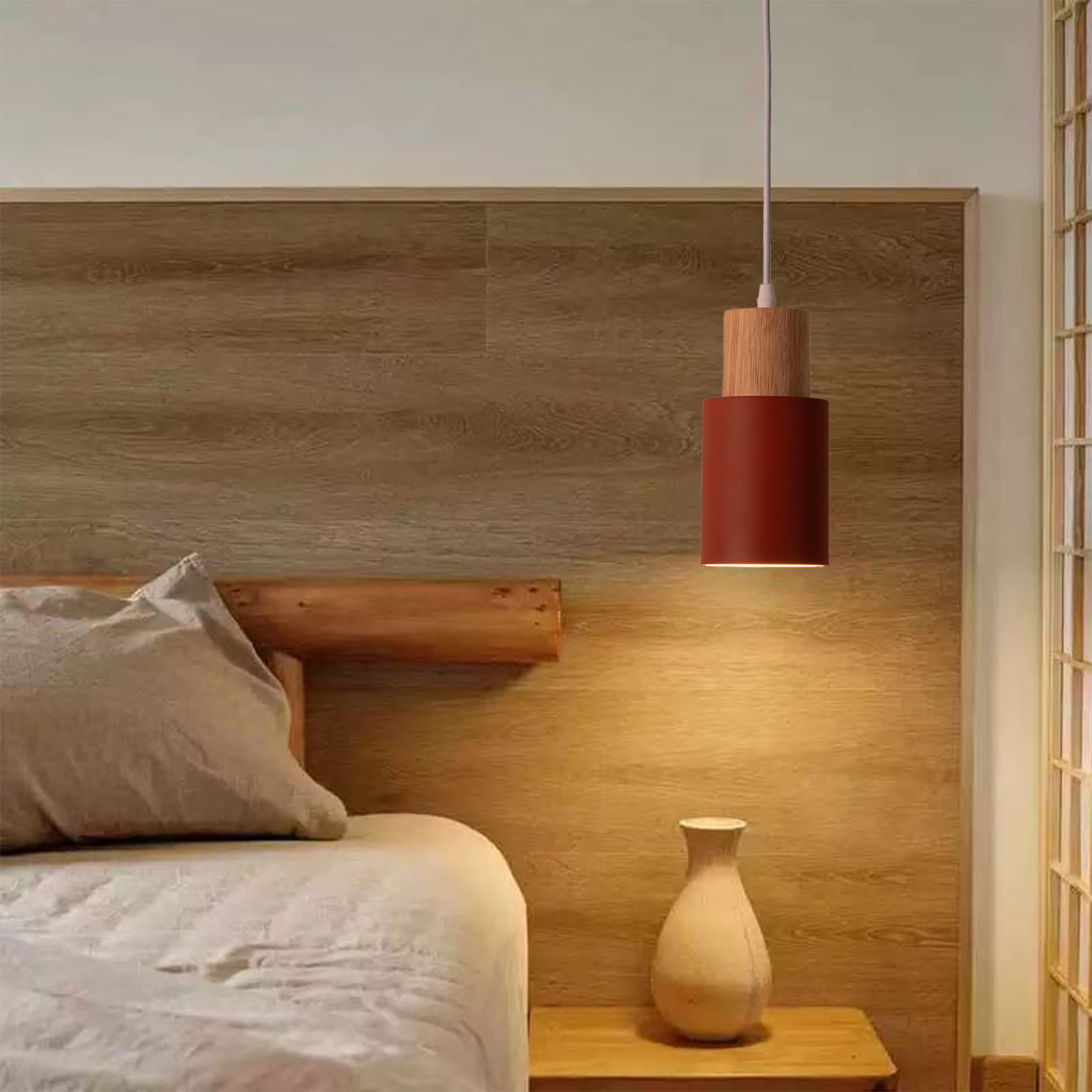 Una escena de dormitorio con una lámpara colgante sobre una mesita de noche junto a una cama con ropa de cama gris.