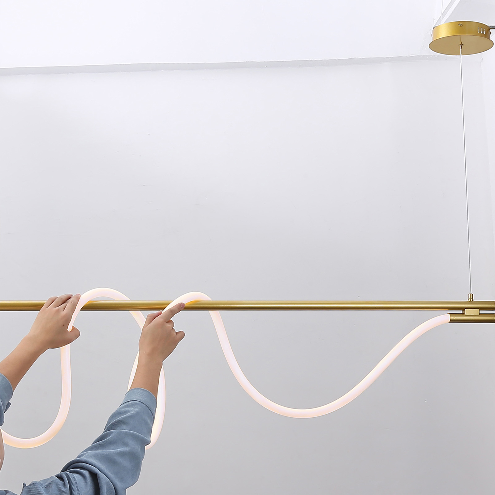 Manos ajustando un tubo LED flexible, parte de una lámpara de techo.