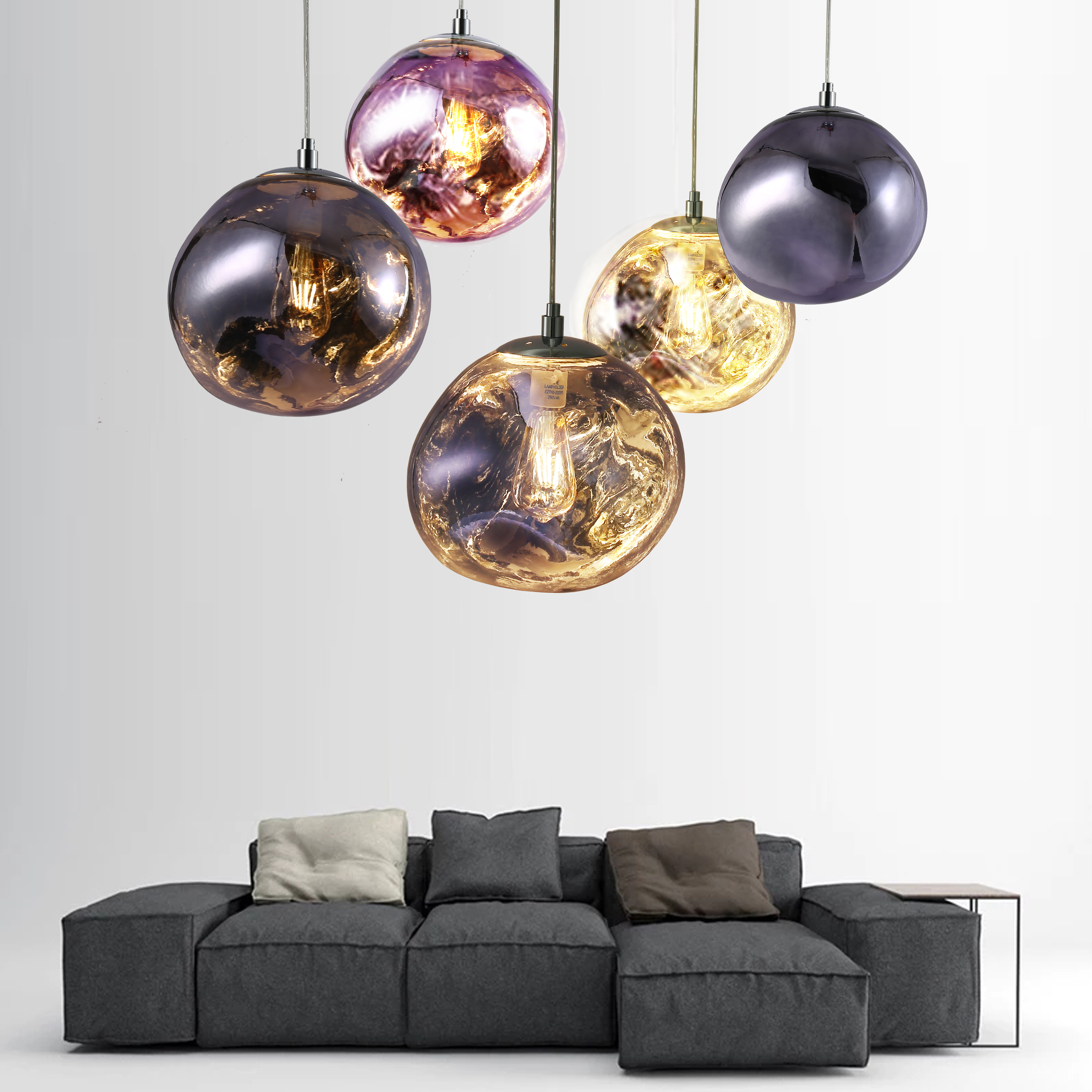 Sala de estar con un sofá gris y varias lámparas colgantes con pantallas de colores.