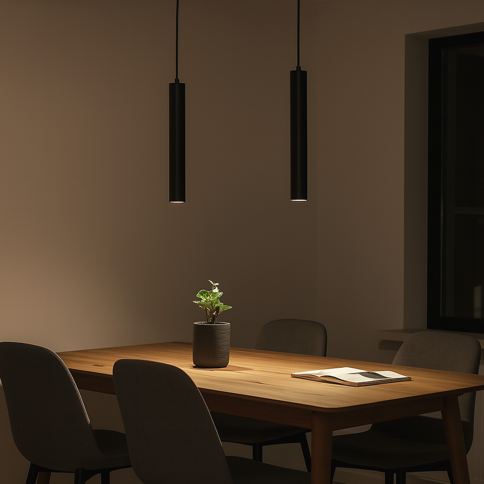 Dos lámparas colgantes cilíndricas negras cuelgan sobre una mesa de comedor en una habitación con poca luz.
