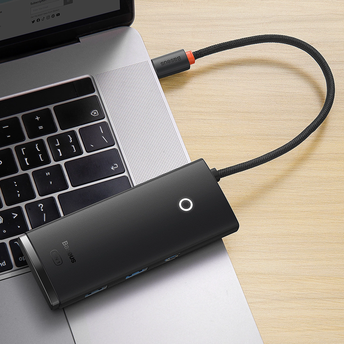 Hub USB-C jest podłączony do laptopa. Posiada wiele portów i pleciony kabel.