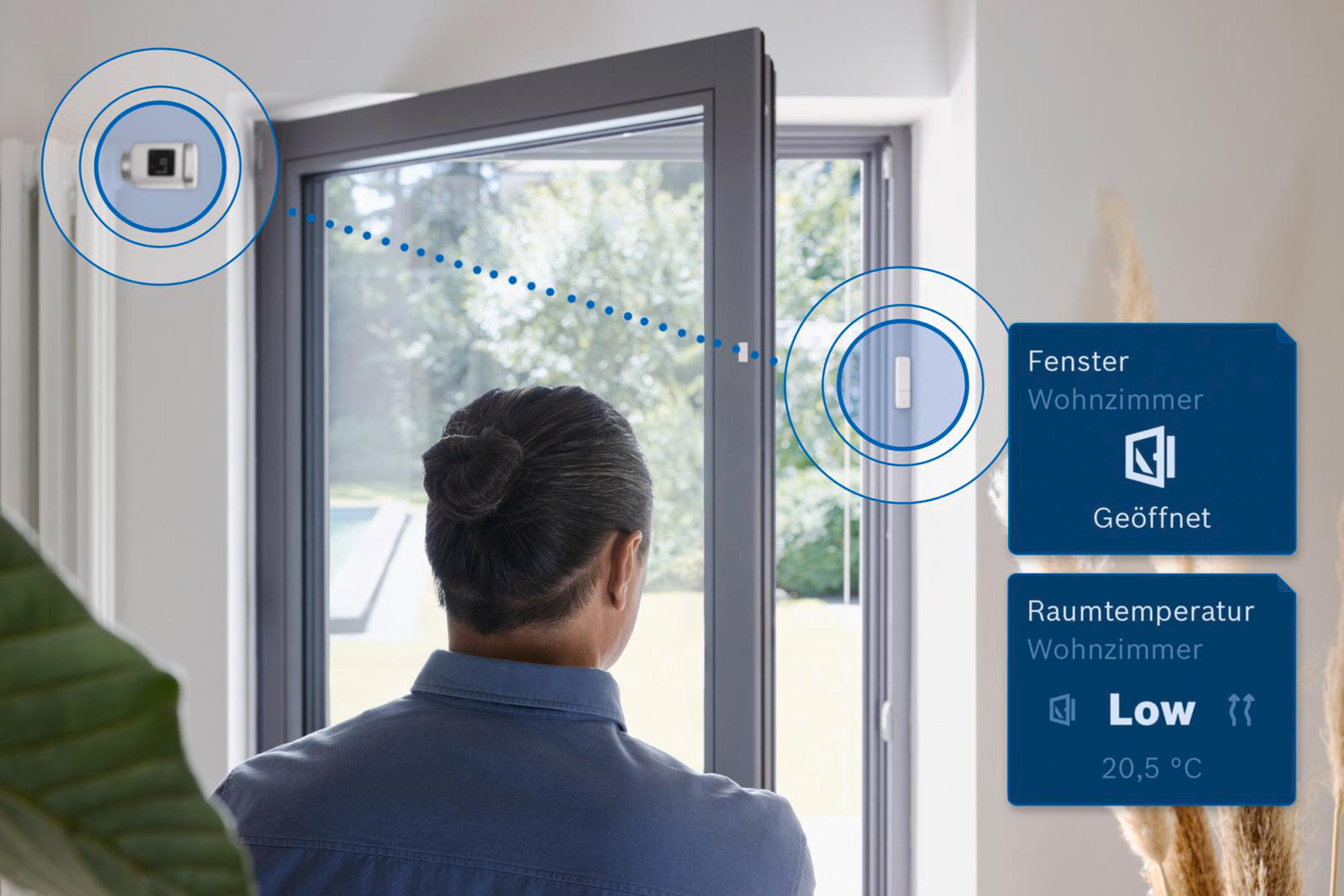 Mann betrachtet Fenster mit Smart-Home-Sensoren und Raumdatenanzeige.