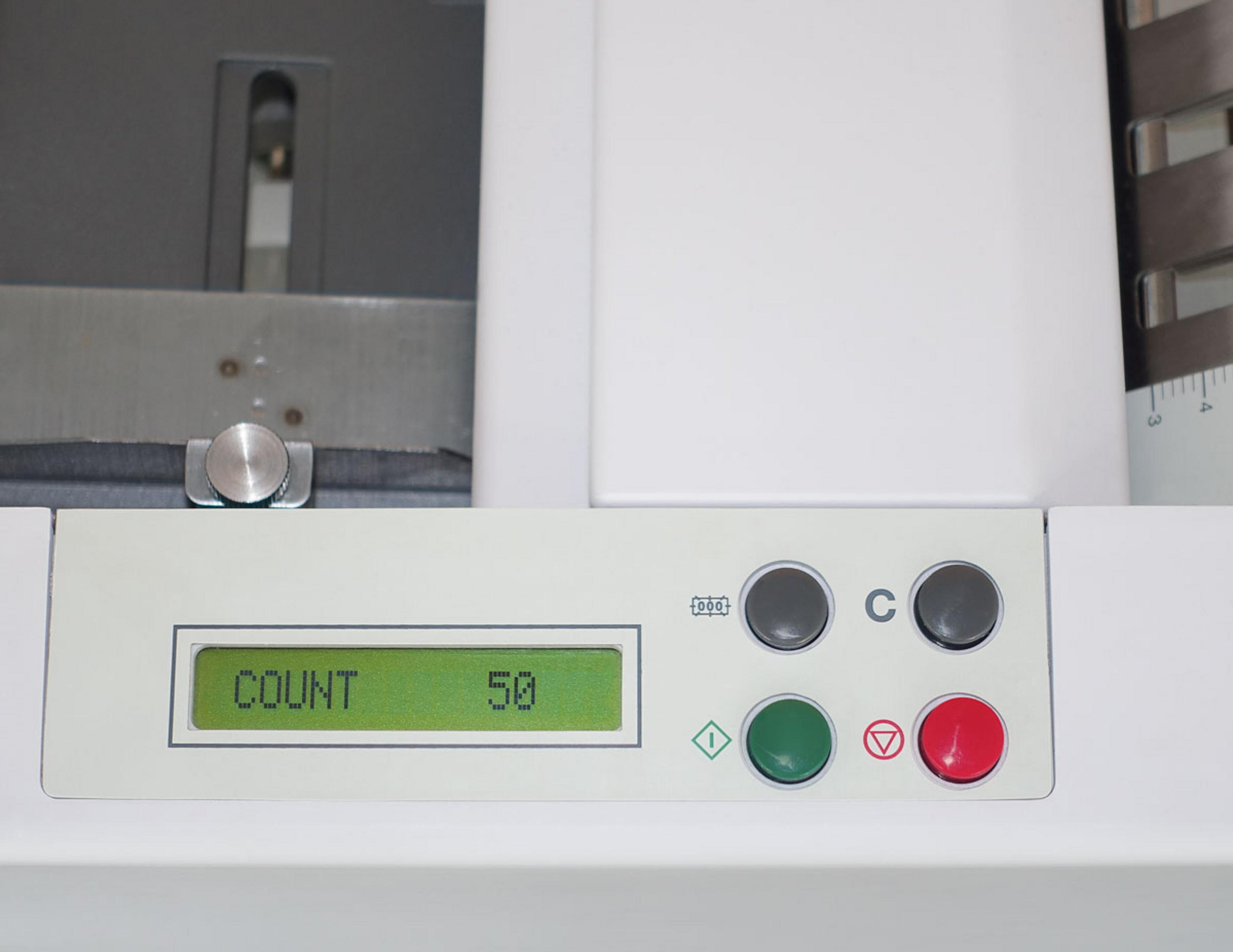 Nahaufnahme eines Maschinenbedienfelds, das "COUNT 50" auf einem grünen Bildschirm mit Tasten anzeigt.