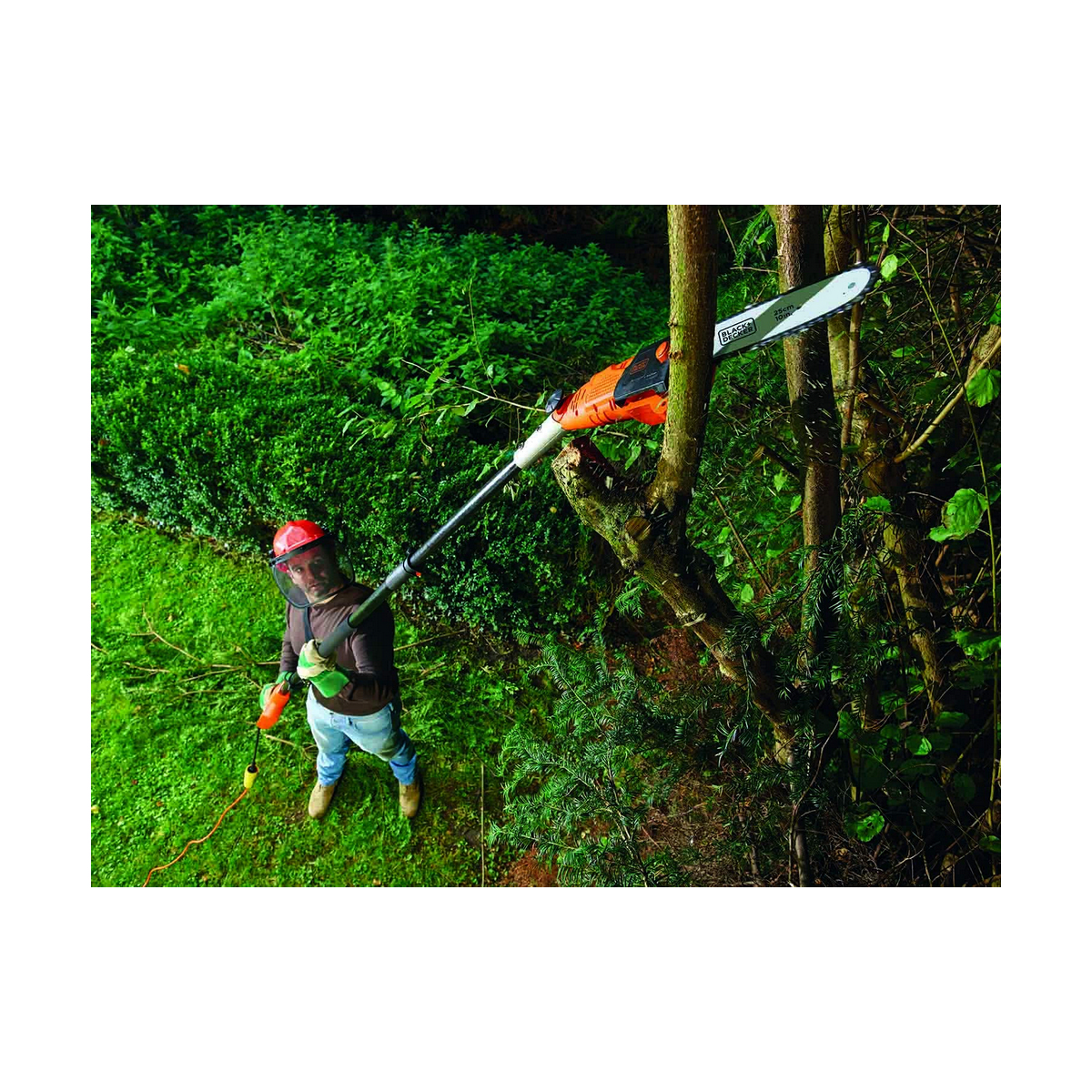 Osoba w kasku i sprzęcie ochronnym używa piły na wysięgniku do przycinania drzewa.