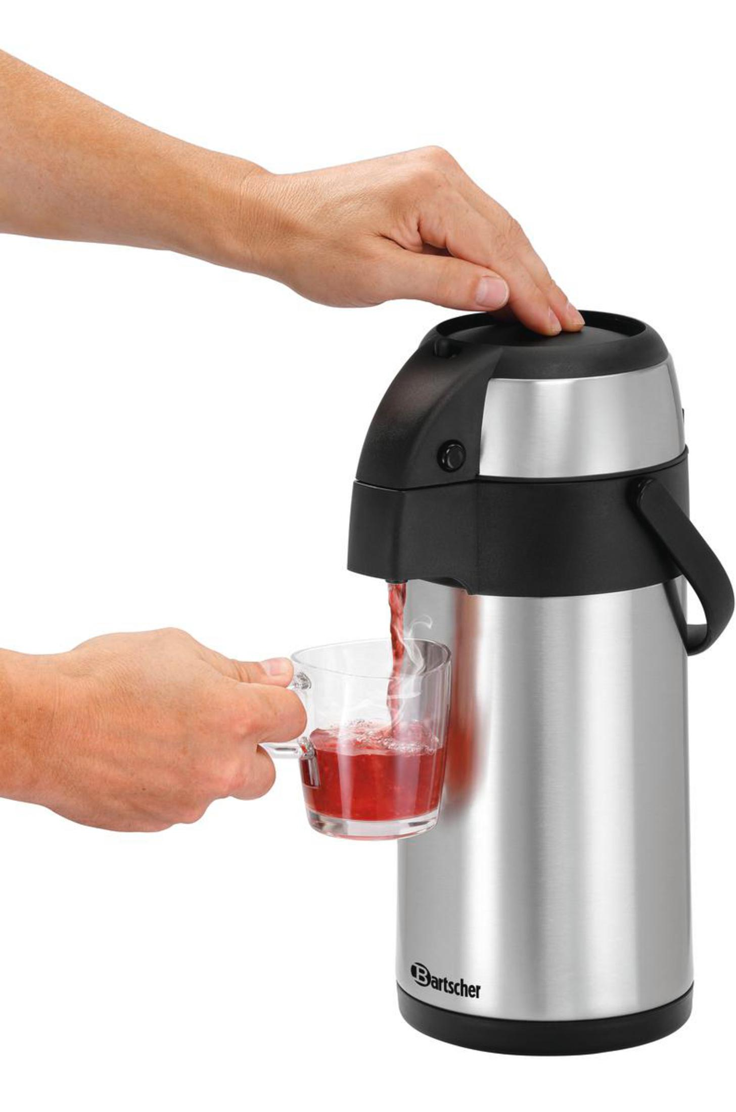 Hand gießt rote Flüssigkeit aus einem silbernen Thermos in ein Glas auf weißem Hintergrund.