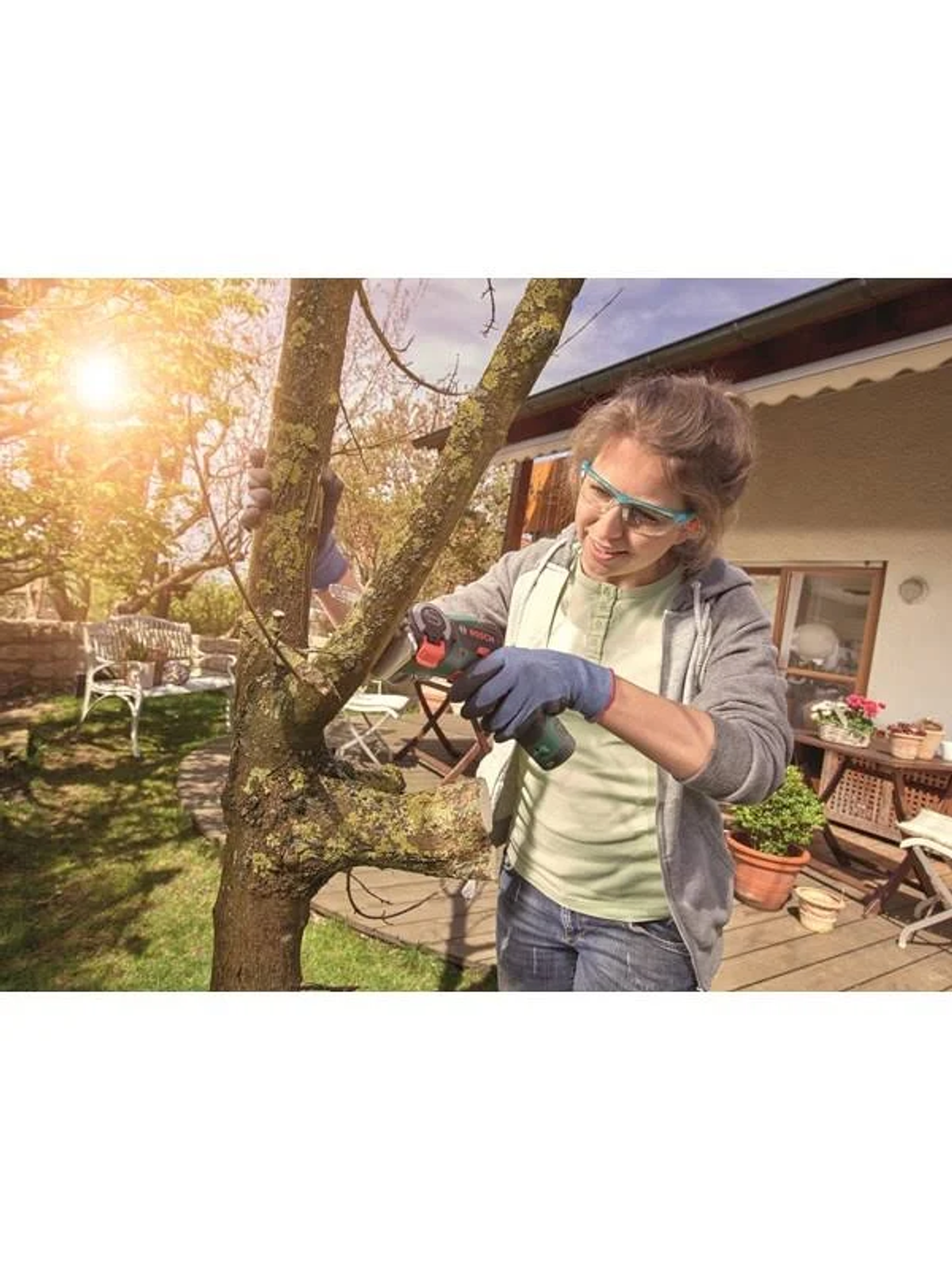 Eine Frau schneidet mit Schutzbrille einen Ast mit einer Bosch EasyCut 12 nanoBLADE Säge.