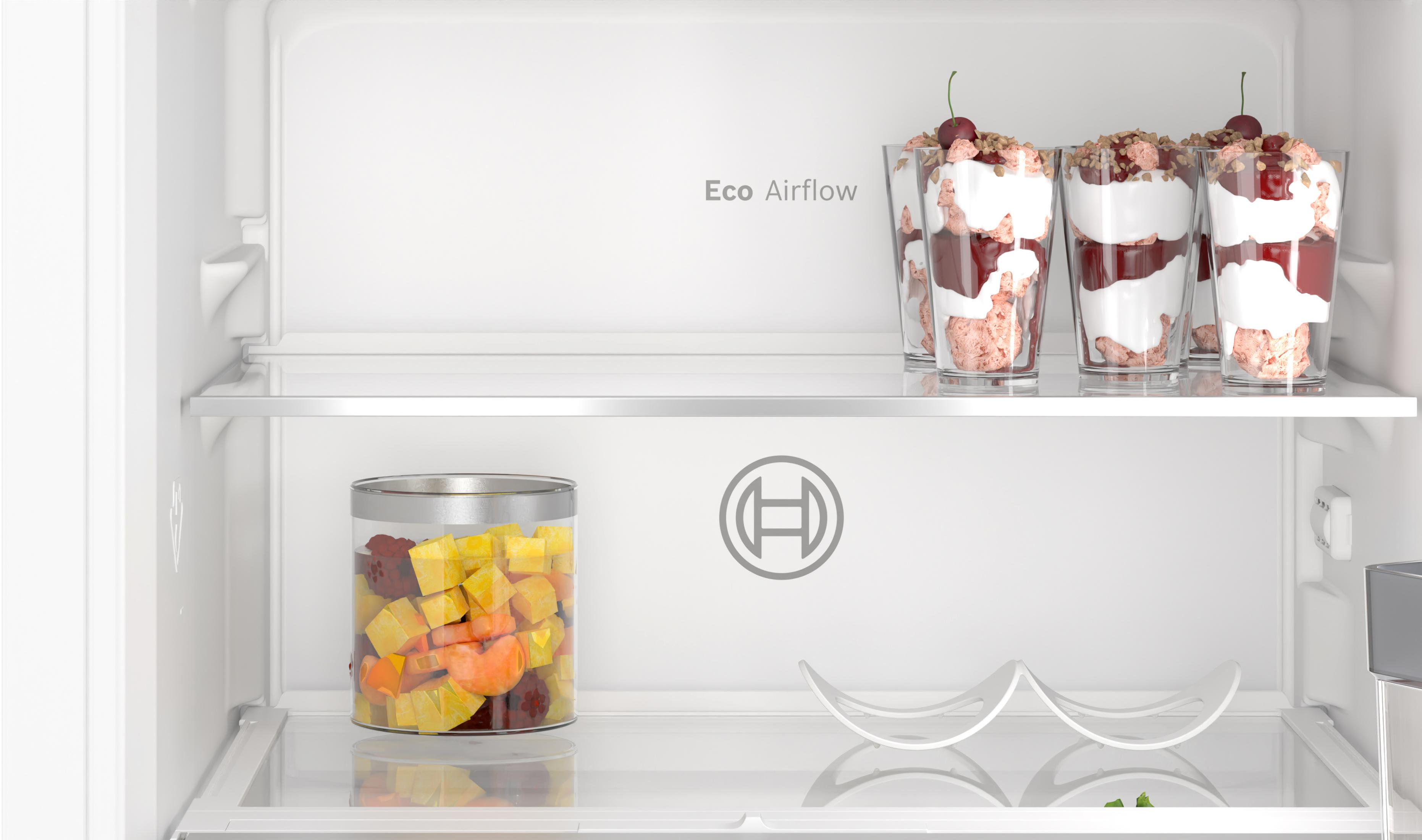 Interno di un frigorifero bianco con ripiani che contengono alimenti, tra cui dessert e frutta. Etichetta Eco Airflow.