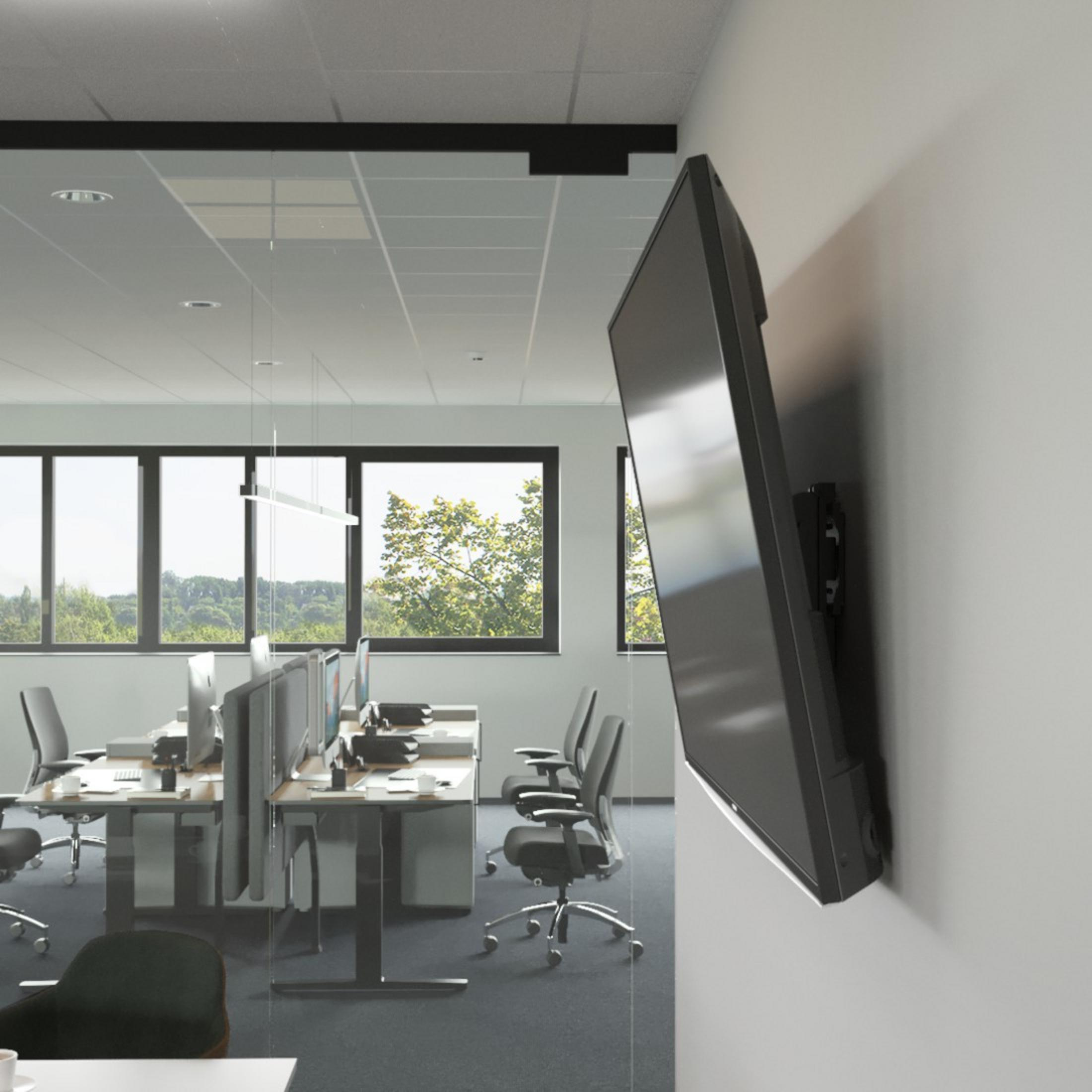 Ein Fernseher, der in einem Büro an der Wand montiert ist. Der Fernseher ist angewinkelt, und das Büro hat Schreibtische und Fenster.