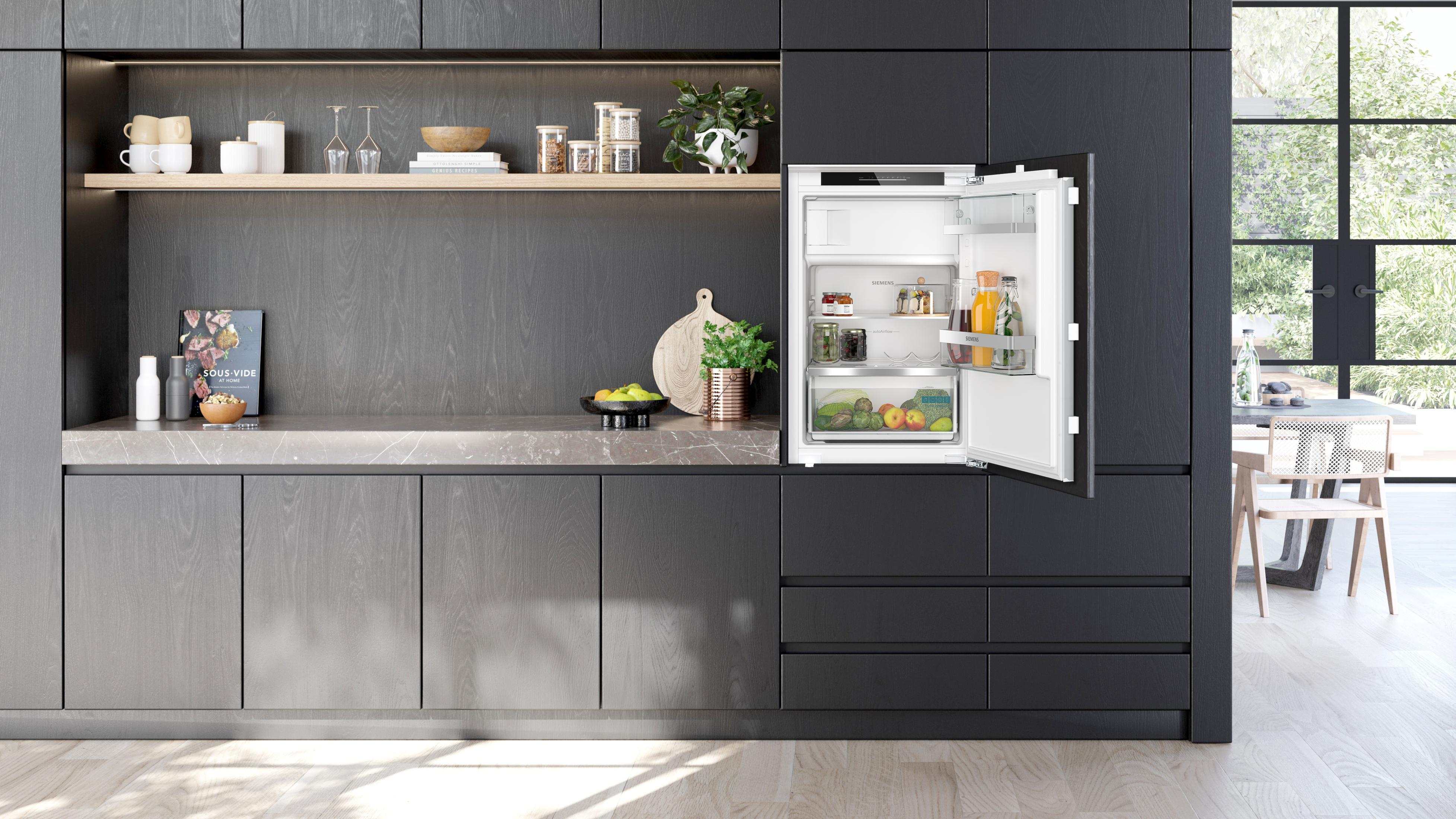 Een keuken met grijze kasten, een marmeren aanrechtblad en een Siemens koelkast met de deur open.