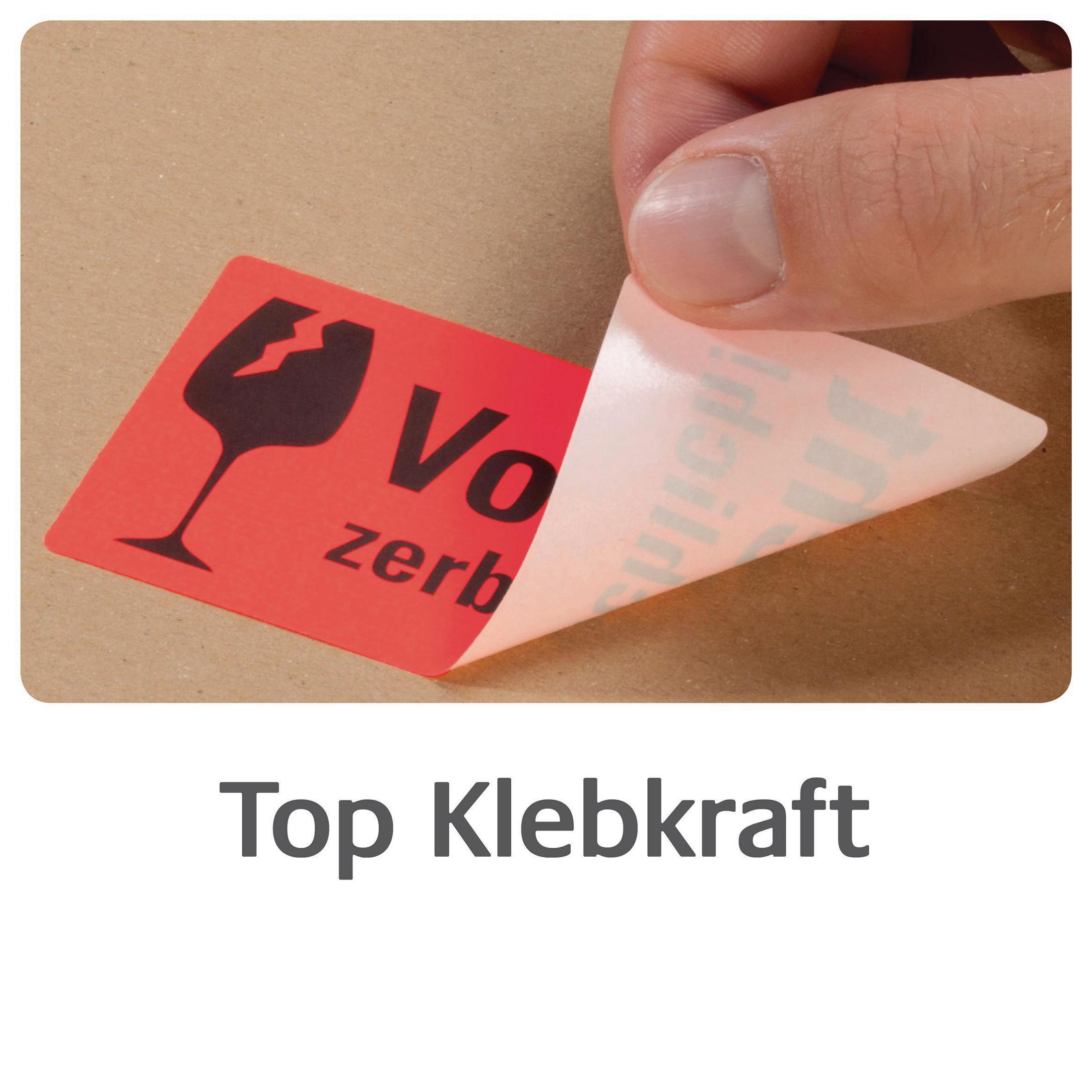 Eine Hand, die ein rotes 'Zerbrechlich'-Etikett von einer Kartonoberfläche abzieht, mit dem Wort 'Top Klebkraft' darunter.
