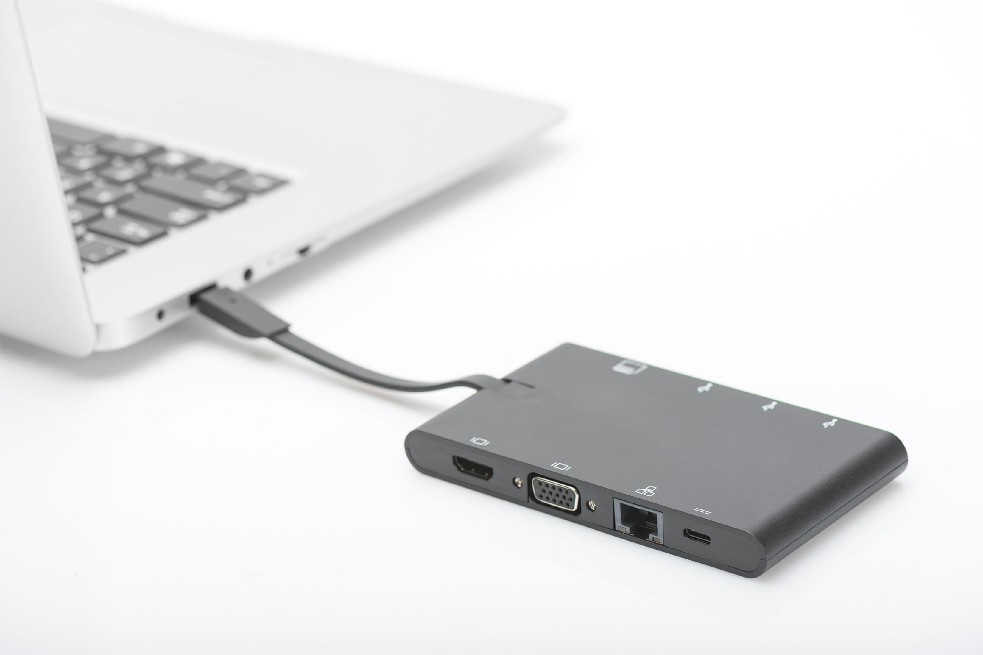 Ein schwarzer Multiport-Adapter ist auf weißem Hintergrund mit einem Laptop verbunden.