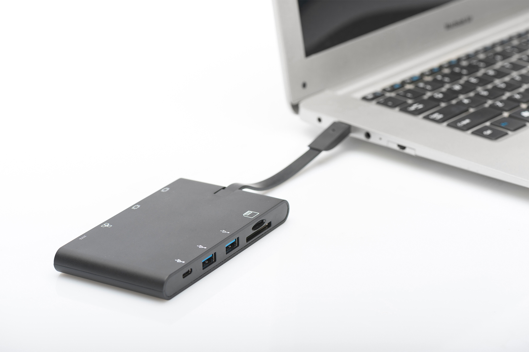 Ein schwarzer Multiport-Adapter ist auf weißem Hintergrund mit einem Laptop verbunden.