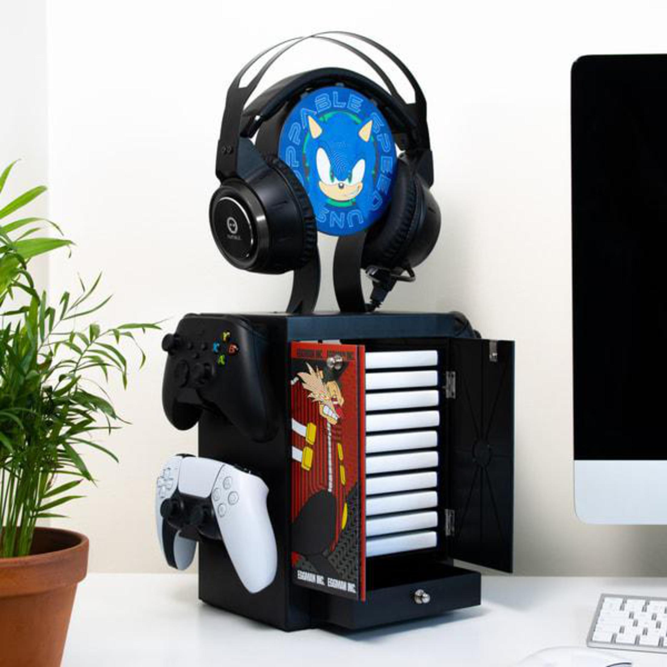 Un armadietto nero per la conservazione dei giochi con cuffie, controller e giochi su una scrivania bianca.