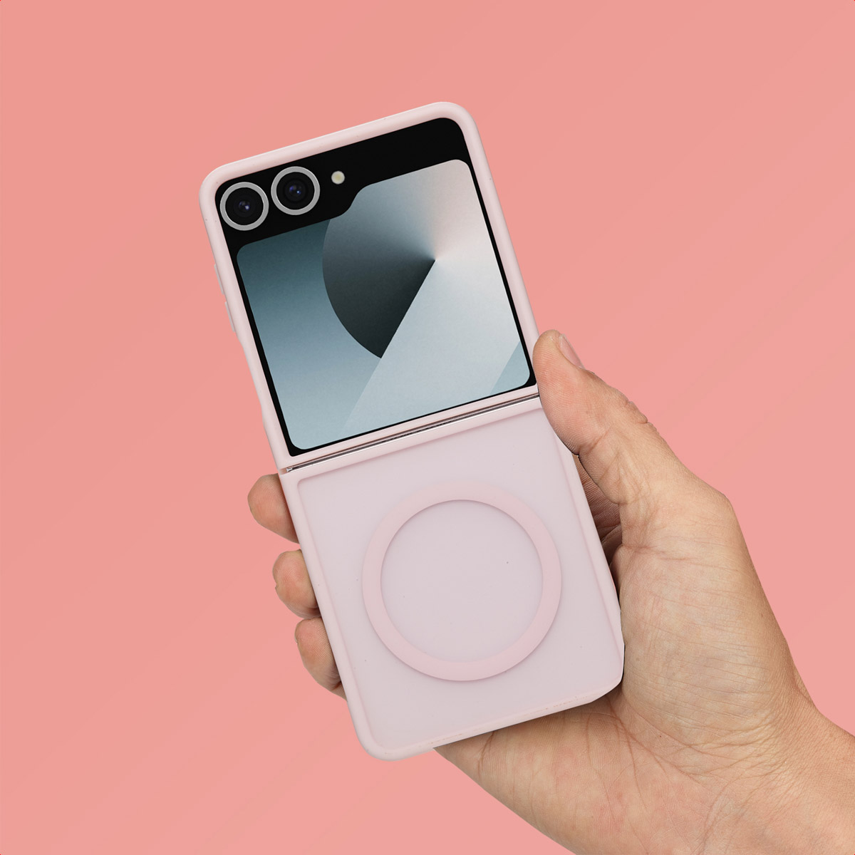 Een roze flip phone hoesje in een hand tegen een roze achtergrond, dat het ontwerp laat zien.