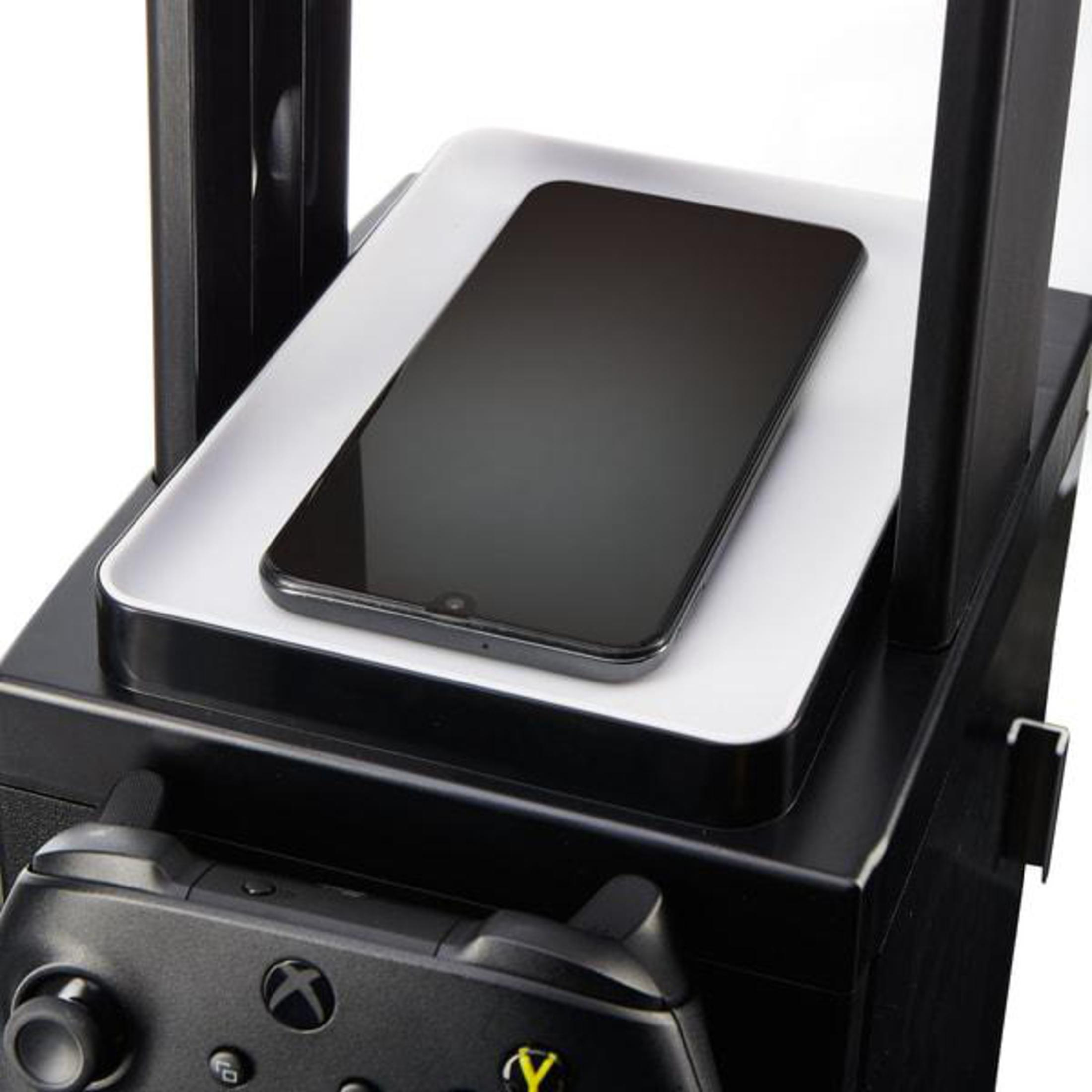 Ein schwarzes Smartphone liegt auf einem weißen Tablett auf einem Gaming-Zubehörständer. An den Seiten befinden sich Gamecontroller.