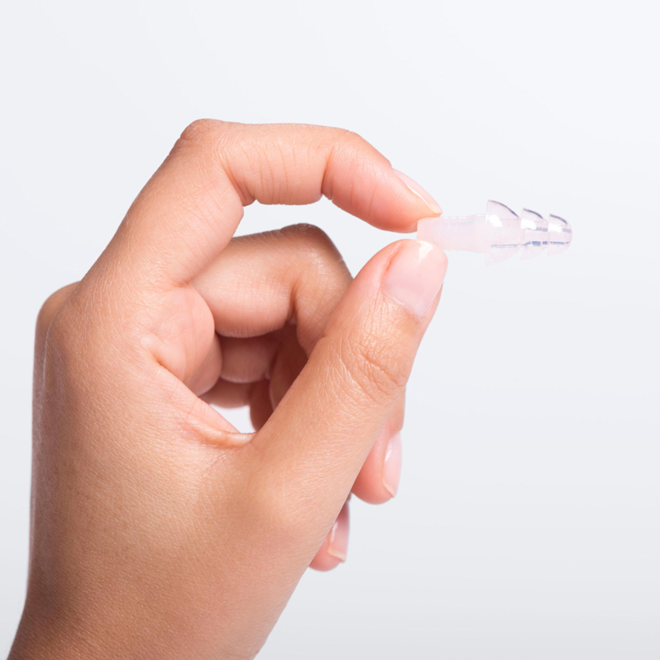 Una mano che tiene un tappo per le orecchie trasparente, a dimostrazione delle sue piccole dimensioni e del suo design.