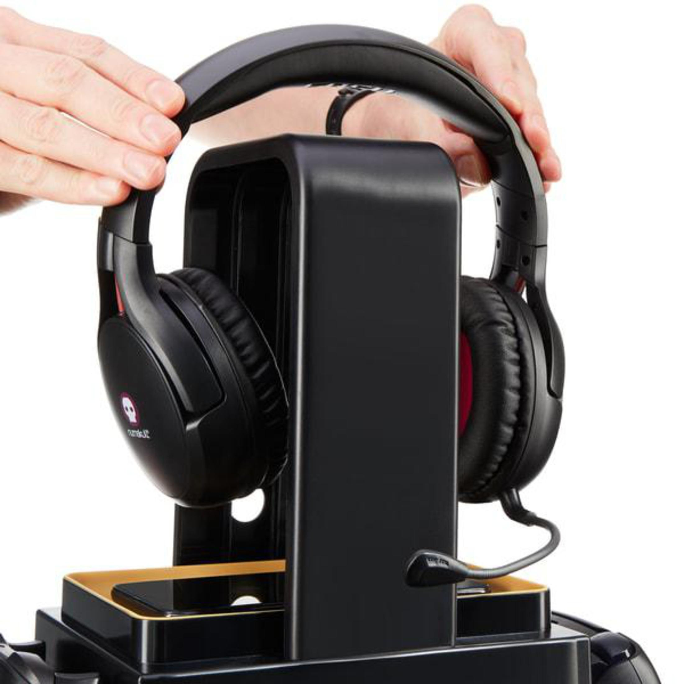 Primo piano di mani che posizionano una cuffia da gioco nera su un supporto nero.
