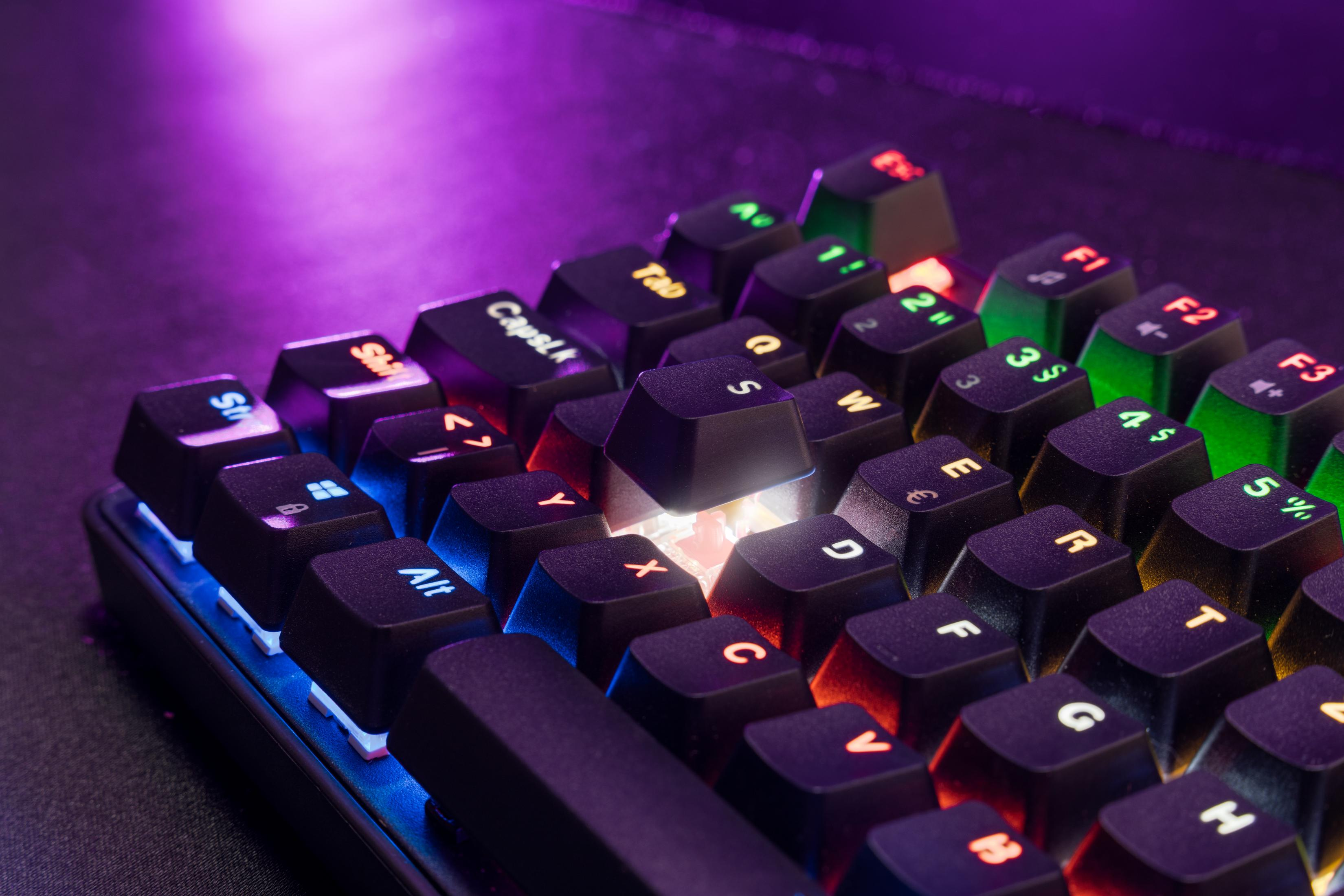 Nahaufnahme von beleuchteten Tasten auf einer schwarzen Tastatur. Farben: Rot, Grün und Blau. Lila Hintergrund.