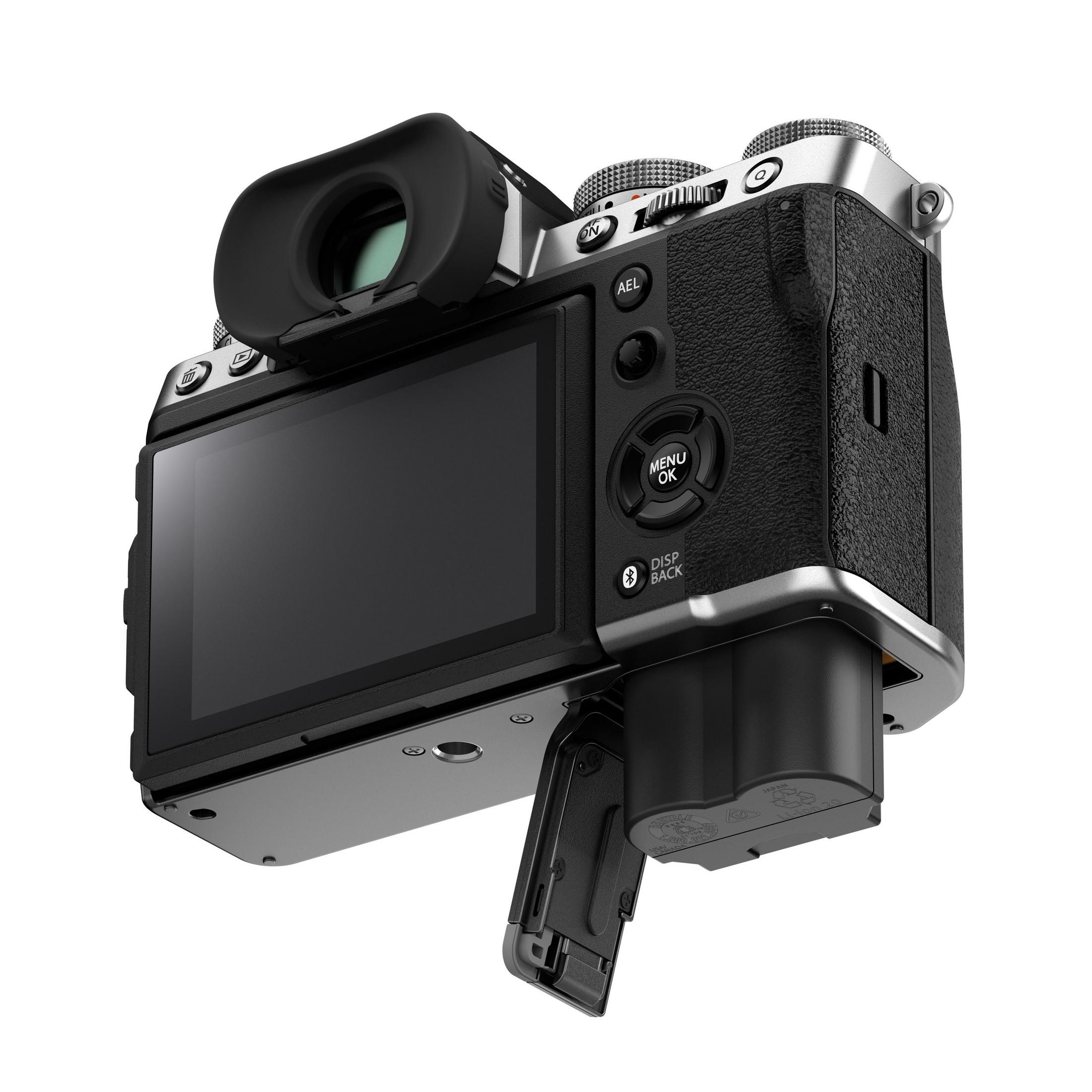 Fujifilm X-T5 camera, angled view, showing rear screen, viewfinder, and battery compartment open.