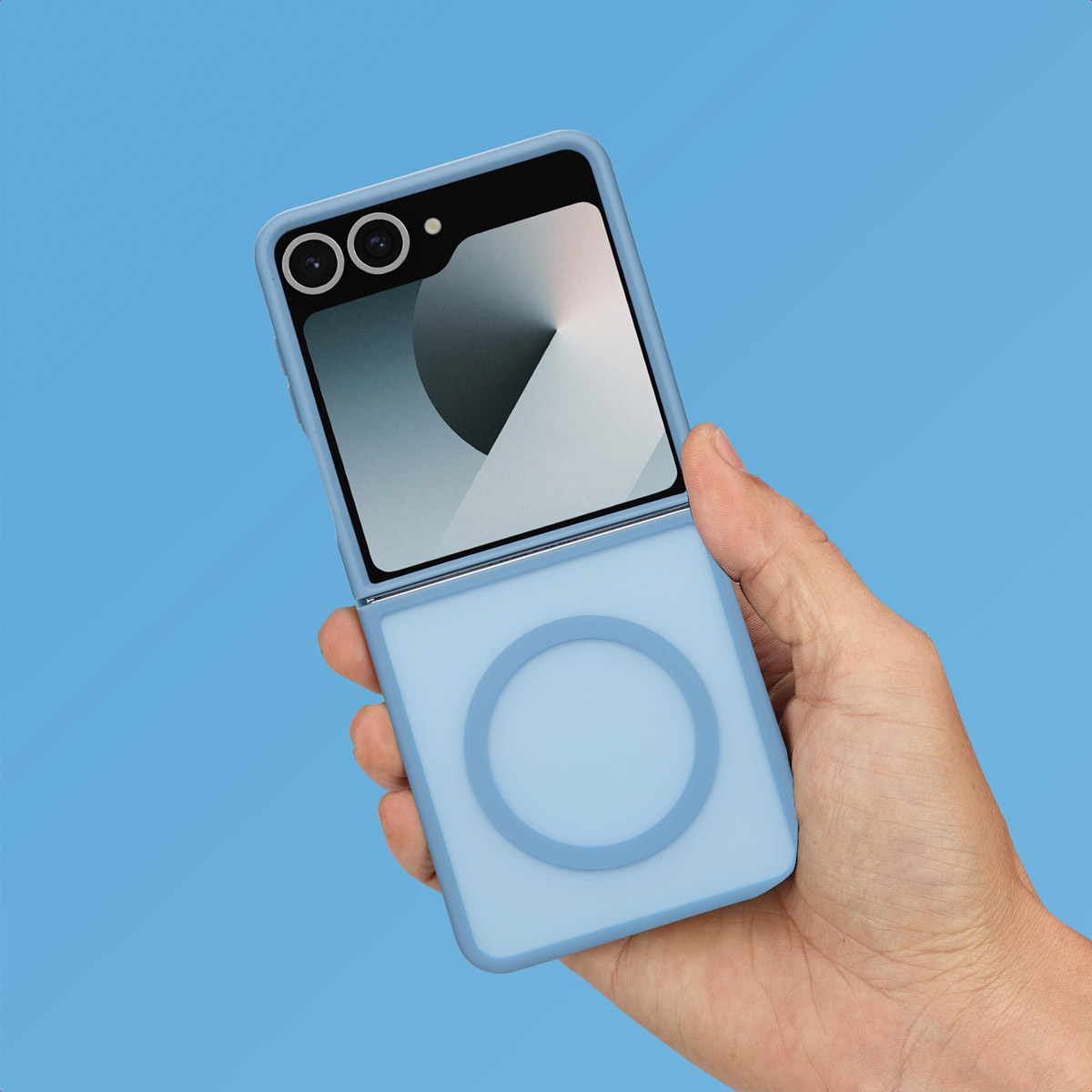 Main tenant une coque de téléphone bleue avec un téléphone à l'intérieur, sur fond bleu. Le téléphone est ouvert.