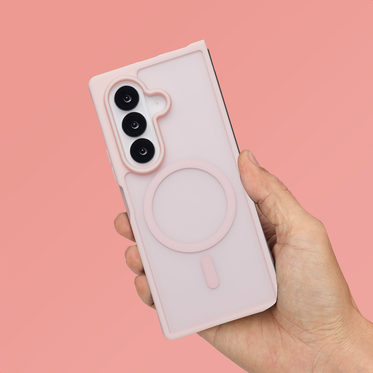 Een hand die een roze telefoon met hoesje vasthoudt, een roze achtergrond en een cirkelontwerp op de hoes.