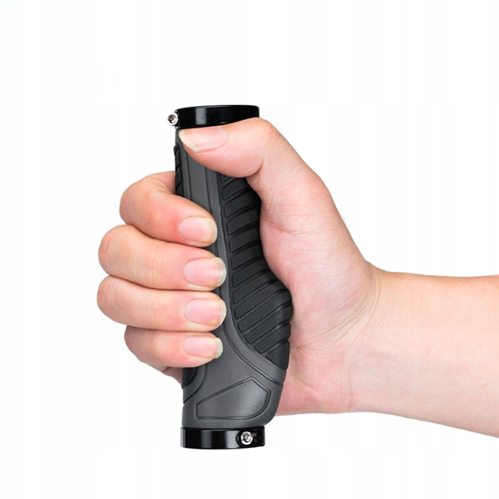 Dłoń mocno chwyta szary uchwyt kierownicy. Palce obejmują uchwyt.