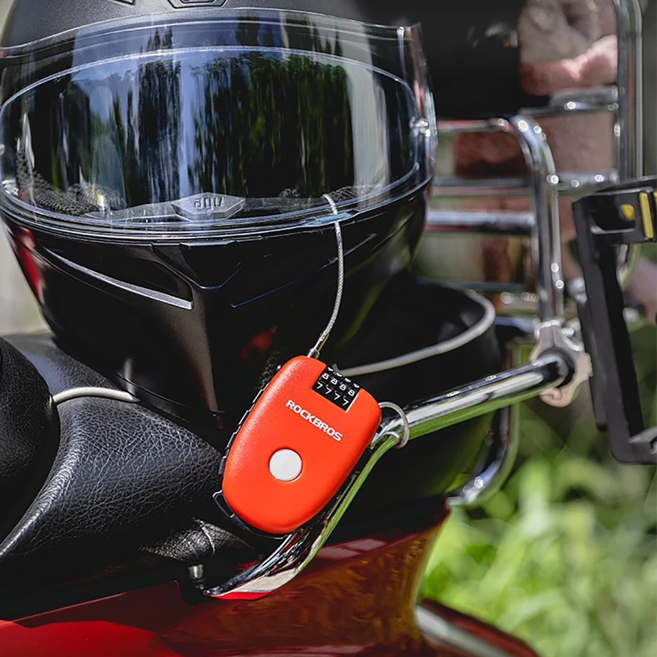 Ein rotes Zahlenschloss ist an einem Motorradhelm und einer Chromstange am Fahrrad befestigt.