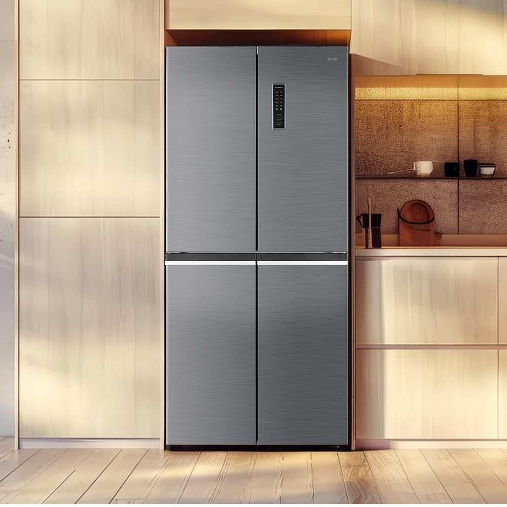 Un refrigerador gris está en una cocina con gabinetes de madera clara y un piso de madera clara.