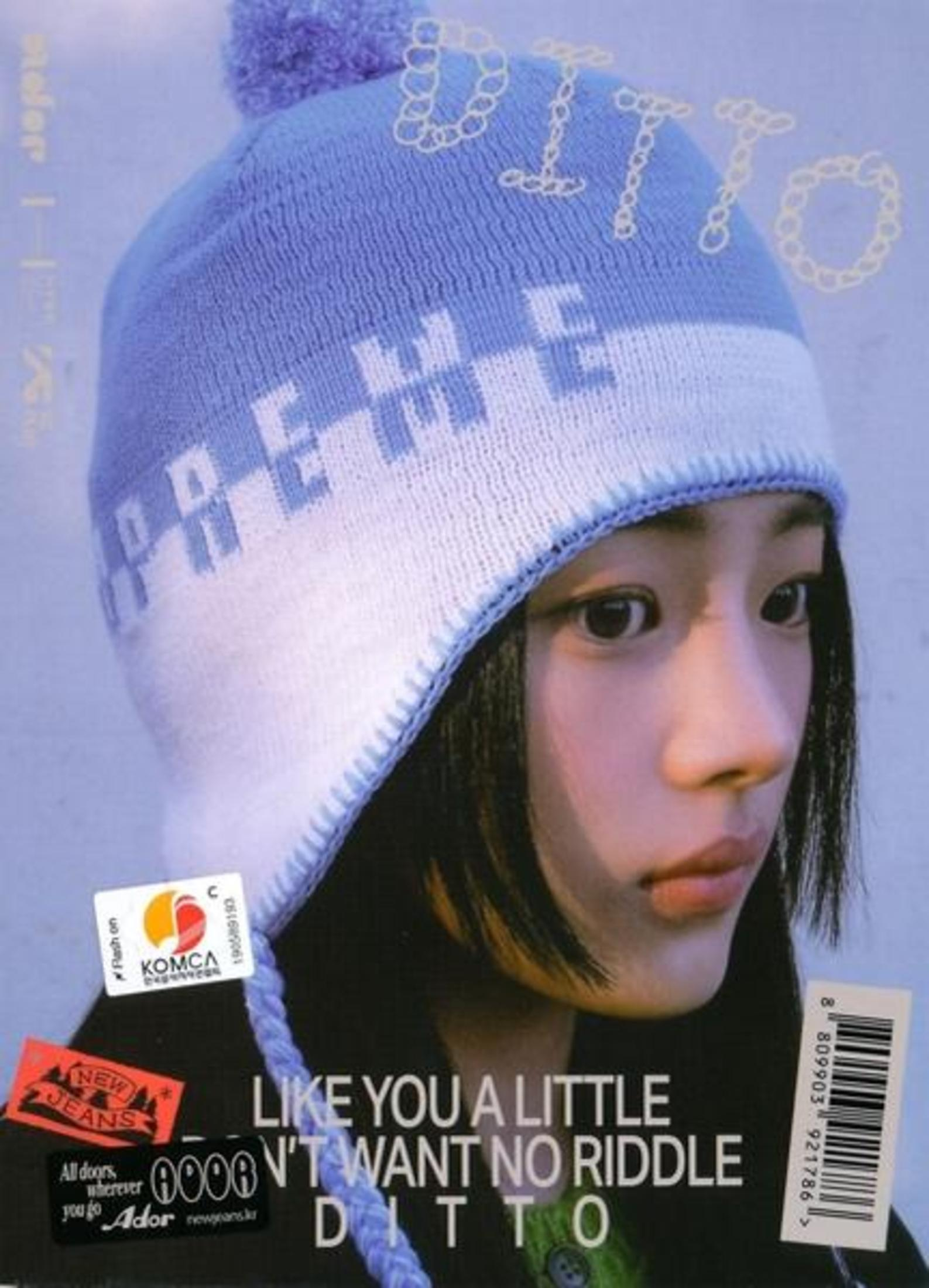 Un membro delle New Jeans indossa un cappello blu e bianco con del testo sopra.