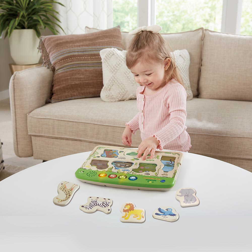 Ein Kind spielt mit einem Tierpuzzle auf einem weißen Tisch vor einer Couch.