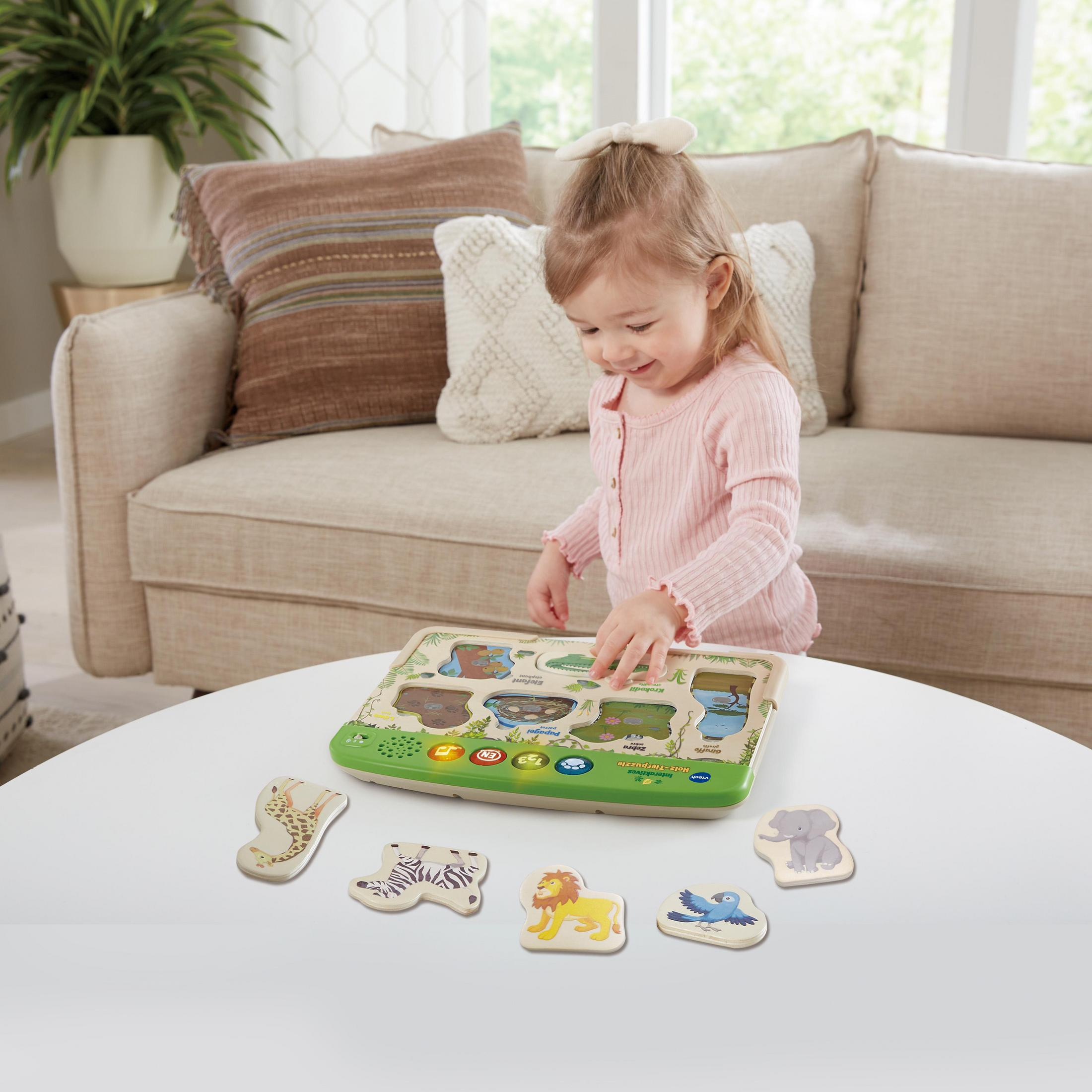 Ein Mädchen spielt mit einem hölzernen Tierpuzzle auf einem weißen Tisch in der Nähe eines beigen Sofas.