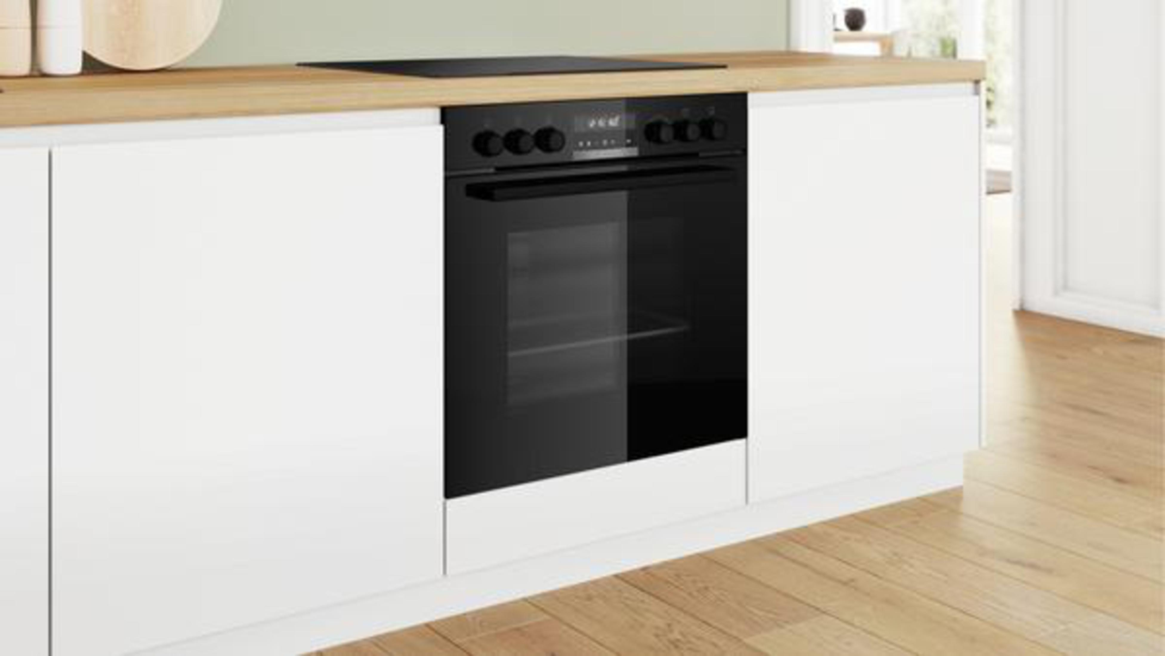 Ein schwarzer Bosch-Backofen, der in weiße Schränke unter einer hellen Holzplatte eingebaut ist.
