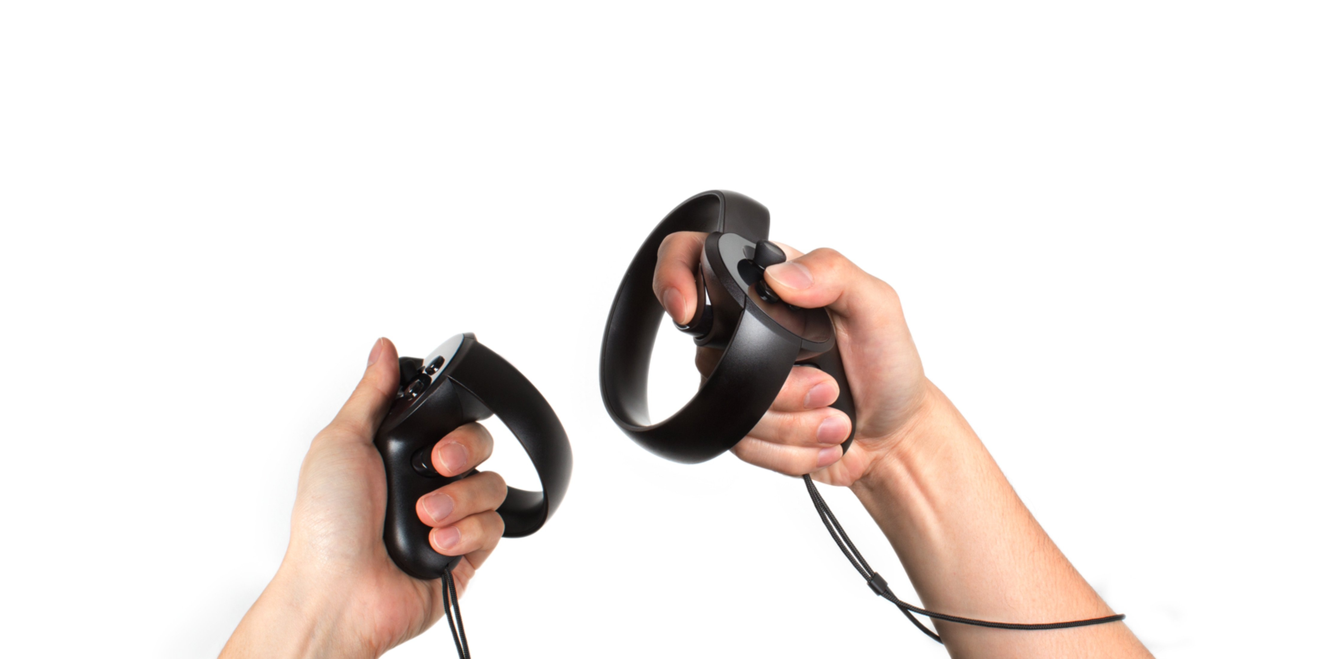 Hände halten zwei schwarze VR-Controller mit Ringgriffen. Weißer Hintergrund.