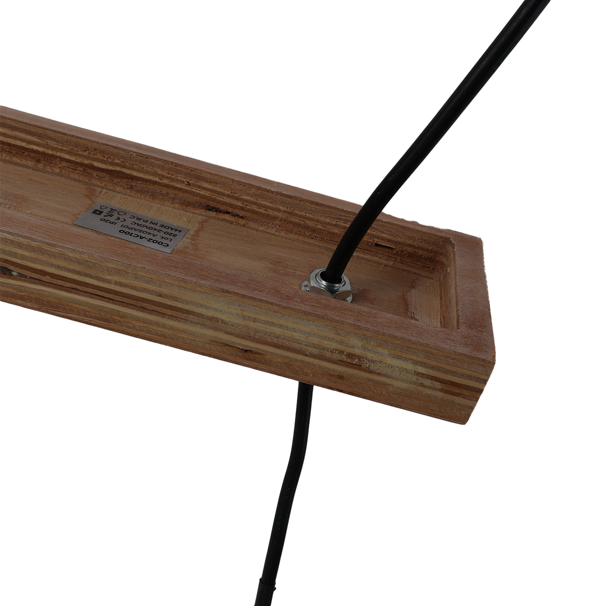 Primer plano de una barra de madera con un agujero y un cable negro que lo atraviesa, contra un fondo blanco.