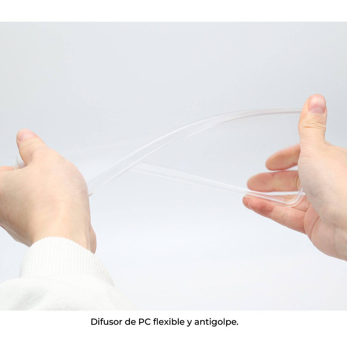 Manos sosteniendo una funda de teléfono de plástico transparente y flexible. La funda está doblada. Fondo blanco.