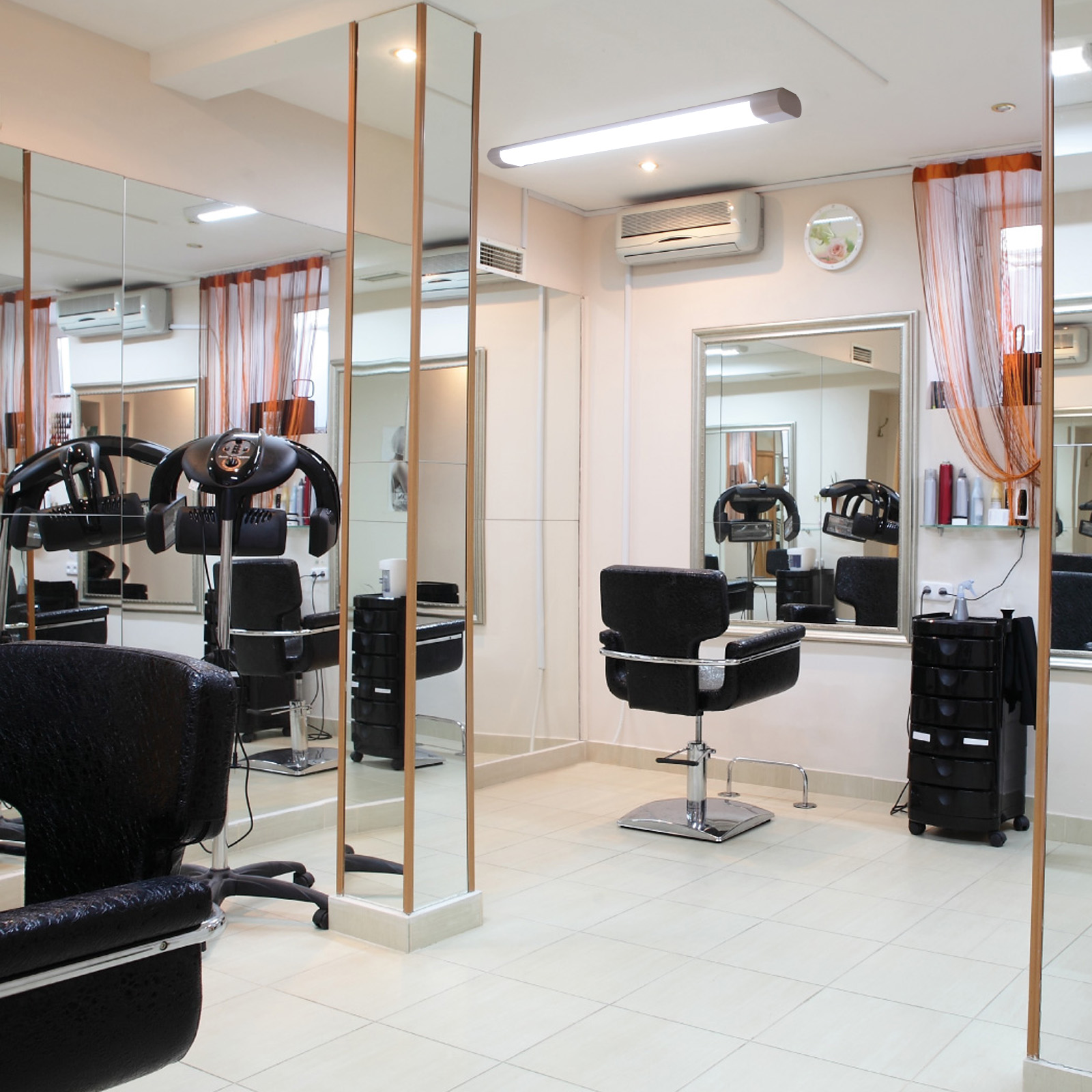 Interior de salón de peluquería con espejos, sillas y equipos, bien iluminado y limpio.