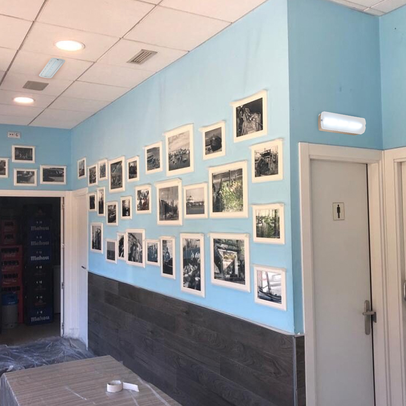 Una habitación cuenta con luces LED montadas en una pared azul adornada con cuadros enmarcados, creando un espacio luminoso y decorativo.