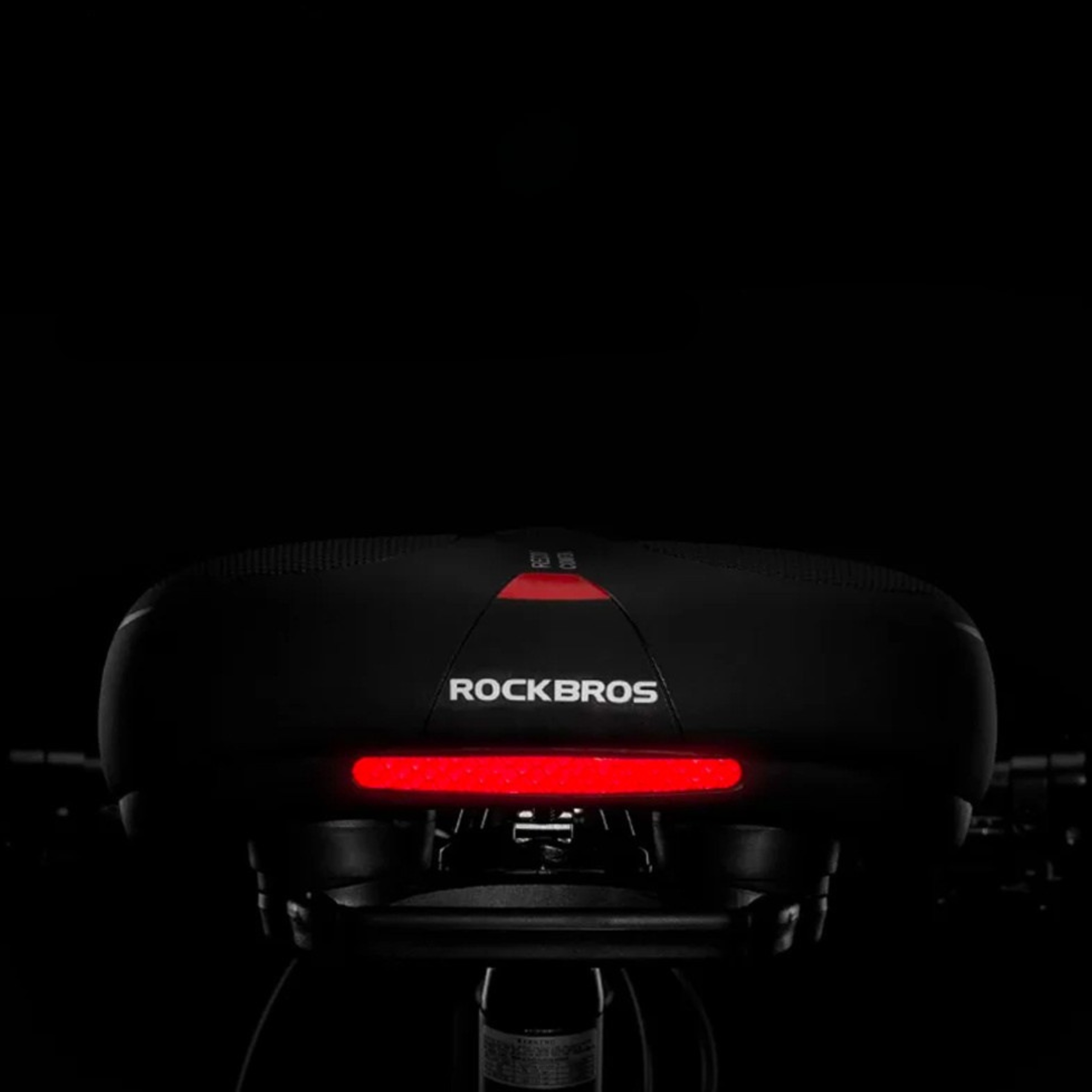 Czarne siodełko rowerowe z czerwonym paskiem świetlnym. Tło jest ciemne.