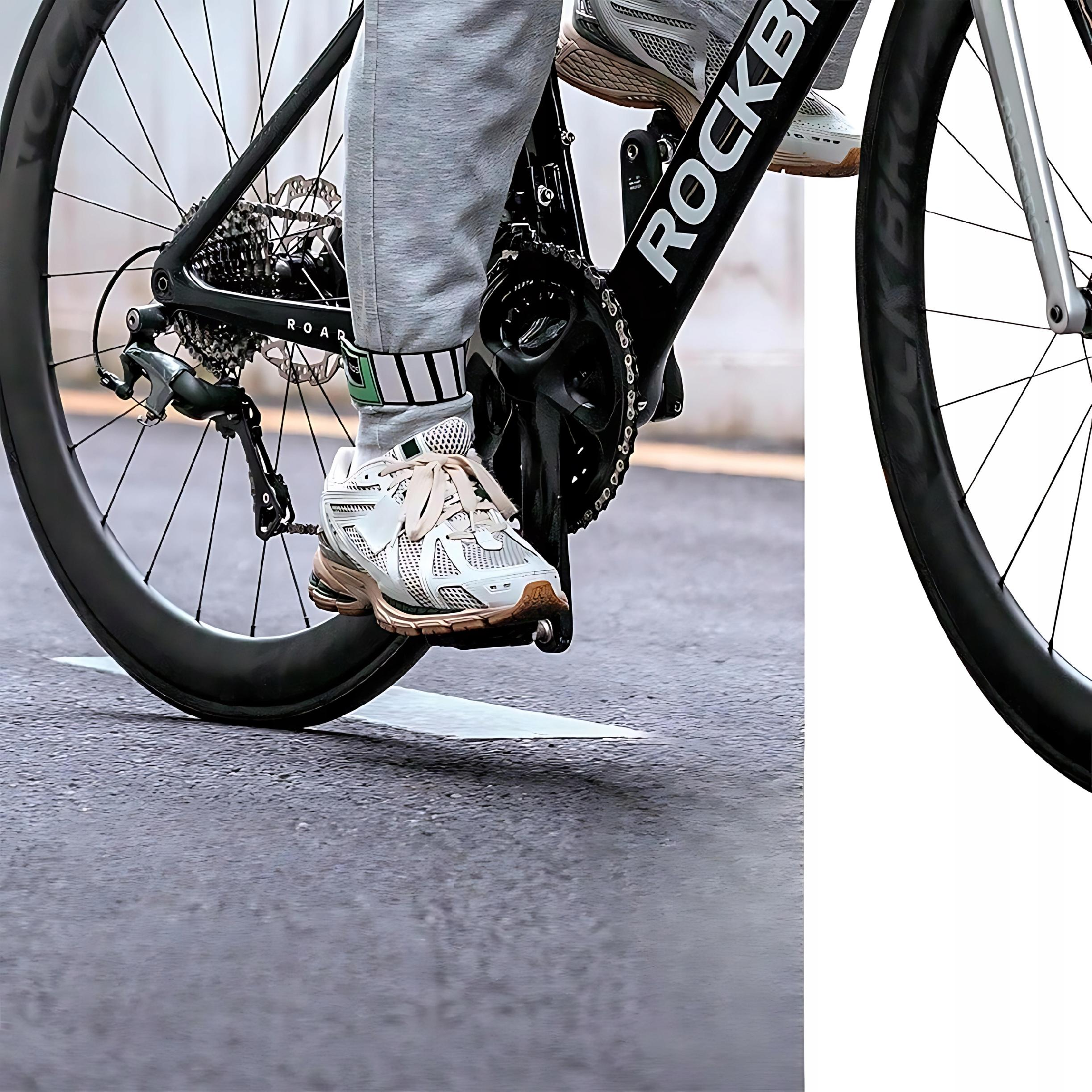 Kolarz na rowerze. Widoczna opaska na kostkę Rockbros. Rower i droga są na zdjęciu.
