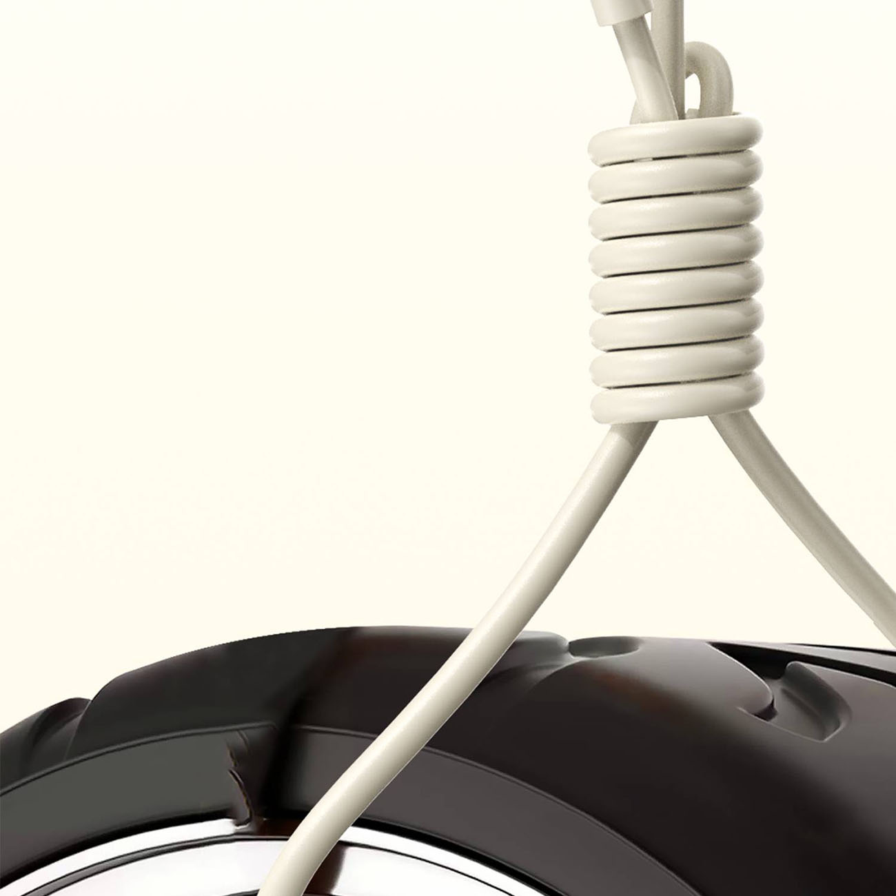 Kremowy kabel USB-C zwinięty. Kabel łączy się z czarnym obiektem w dolnej części obrazu.