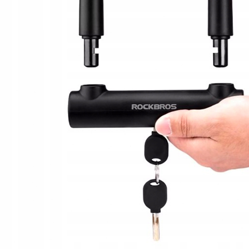 Ręka wkłada klucz do zamka rowerowego, z dwoma zapasowymi kluczami. Zamek jest czarny.